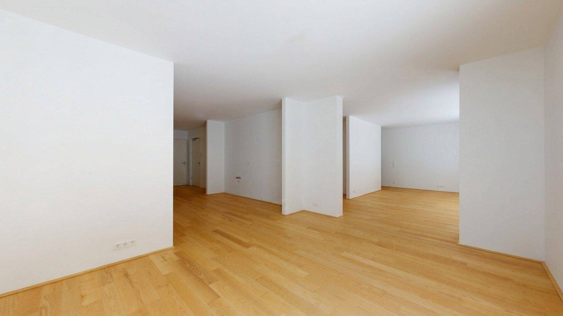 Leerer Raum mit hellem Holzboden und weißen Wänden, bereit für individuelle Gestaltung.