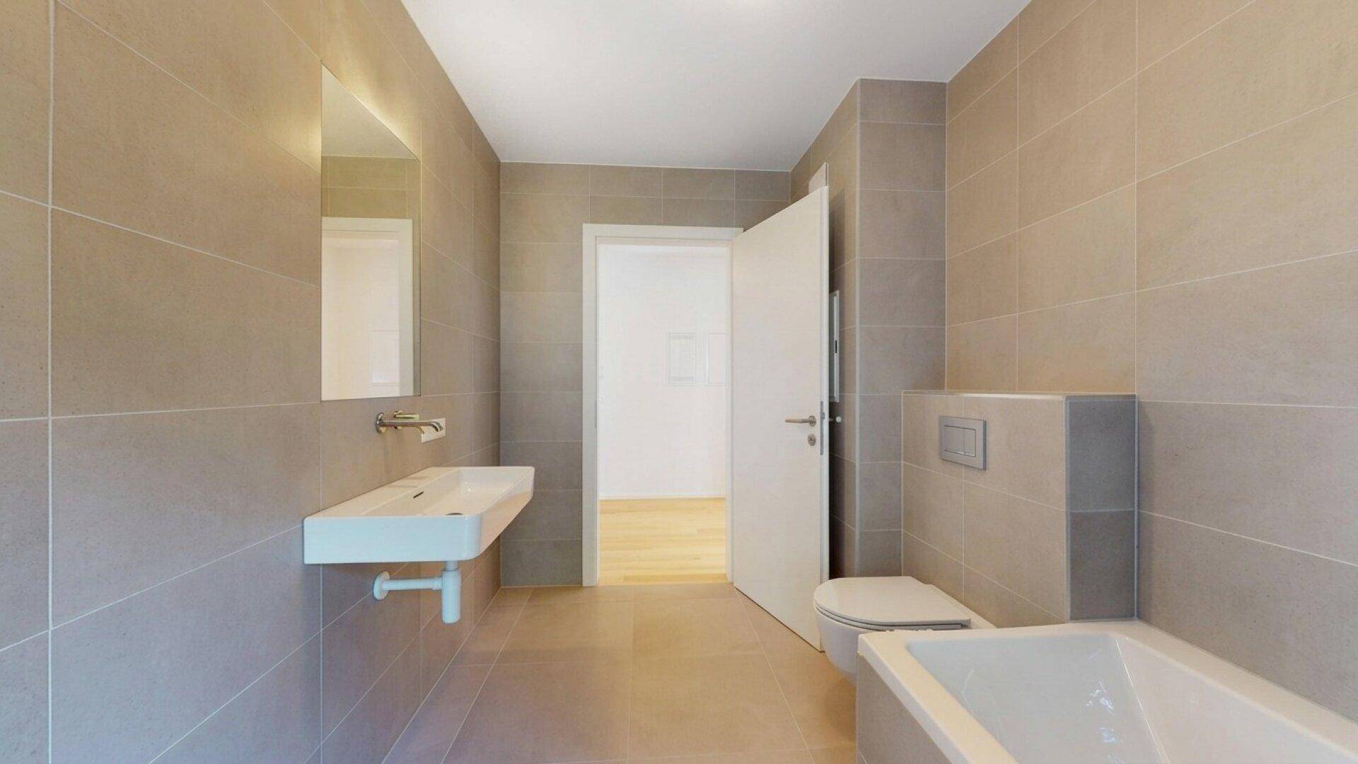 Helles Badezimmer mit modernen Fliesen, wandhängendem WC und elegantem Waschbecken.