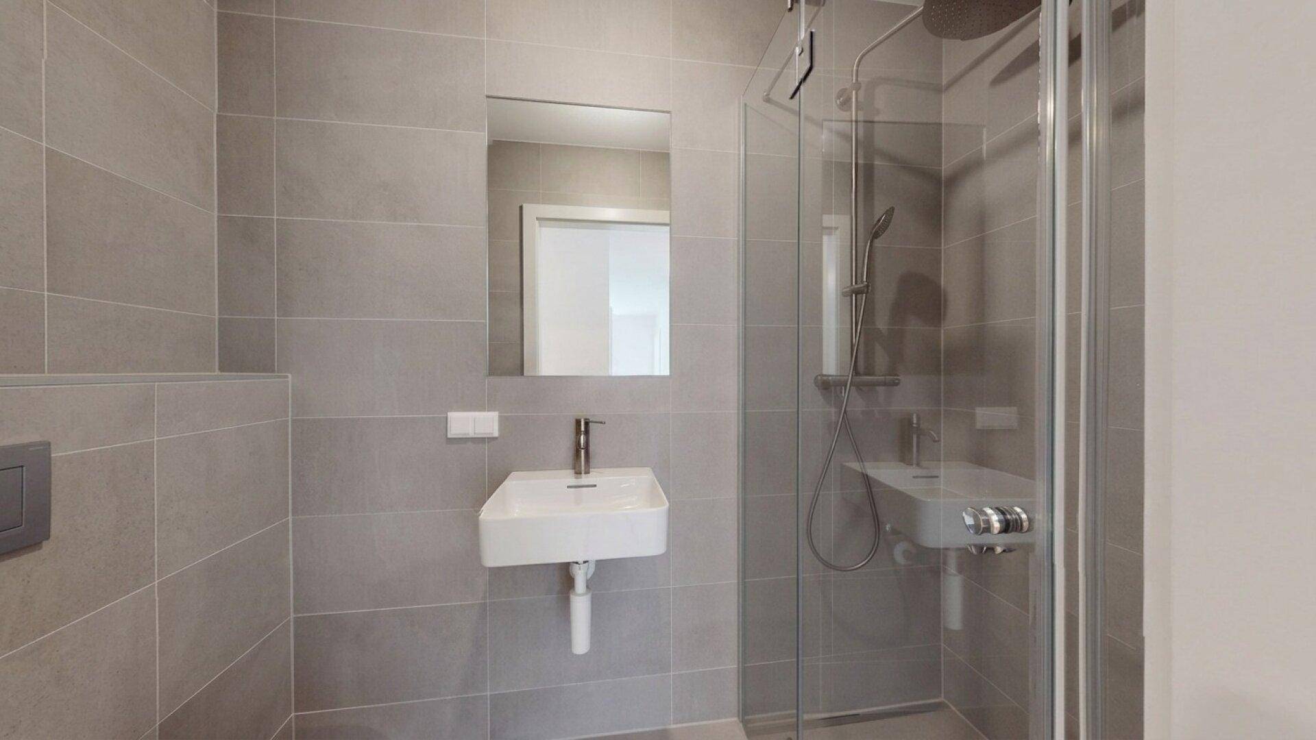 Modernes Badezimmer mit begehbarer Dusche, Glasabtrennung und kleinem Waschbecken.