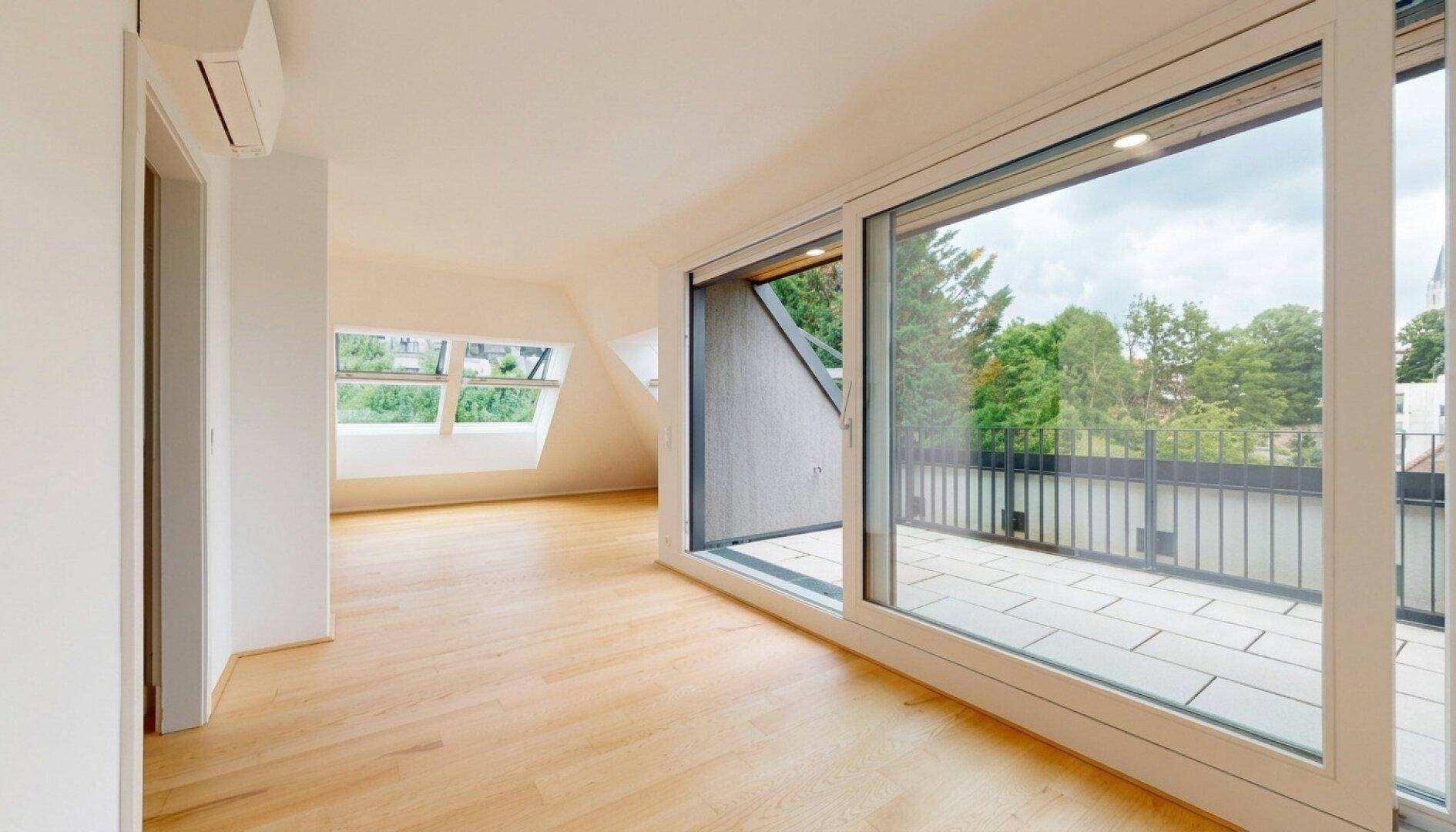 Geräumiger Wohnbereich mit Holzboden, großen Schiebetüren und Zugang zu einer Terrasse.