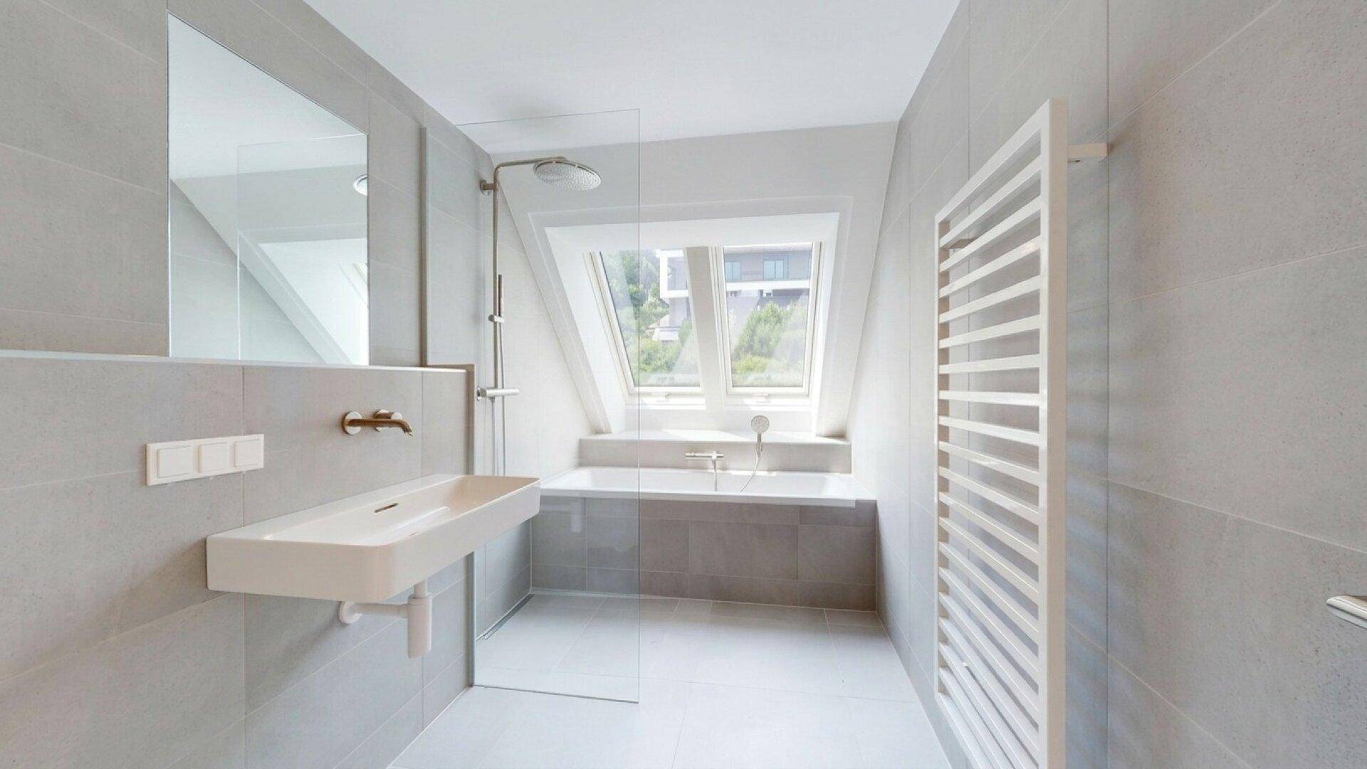 Helles Badezimmer mit Badewanne, Dusche, modernem Waschtisch und beheiztem Handtuchhalter.