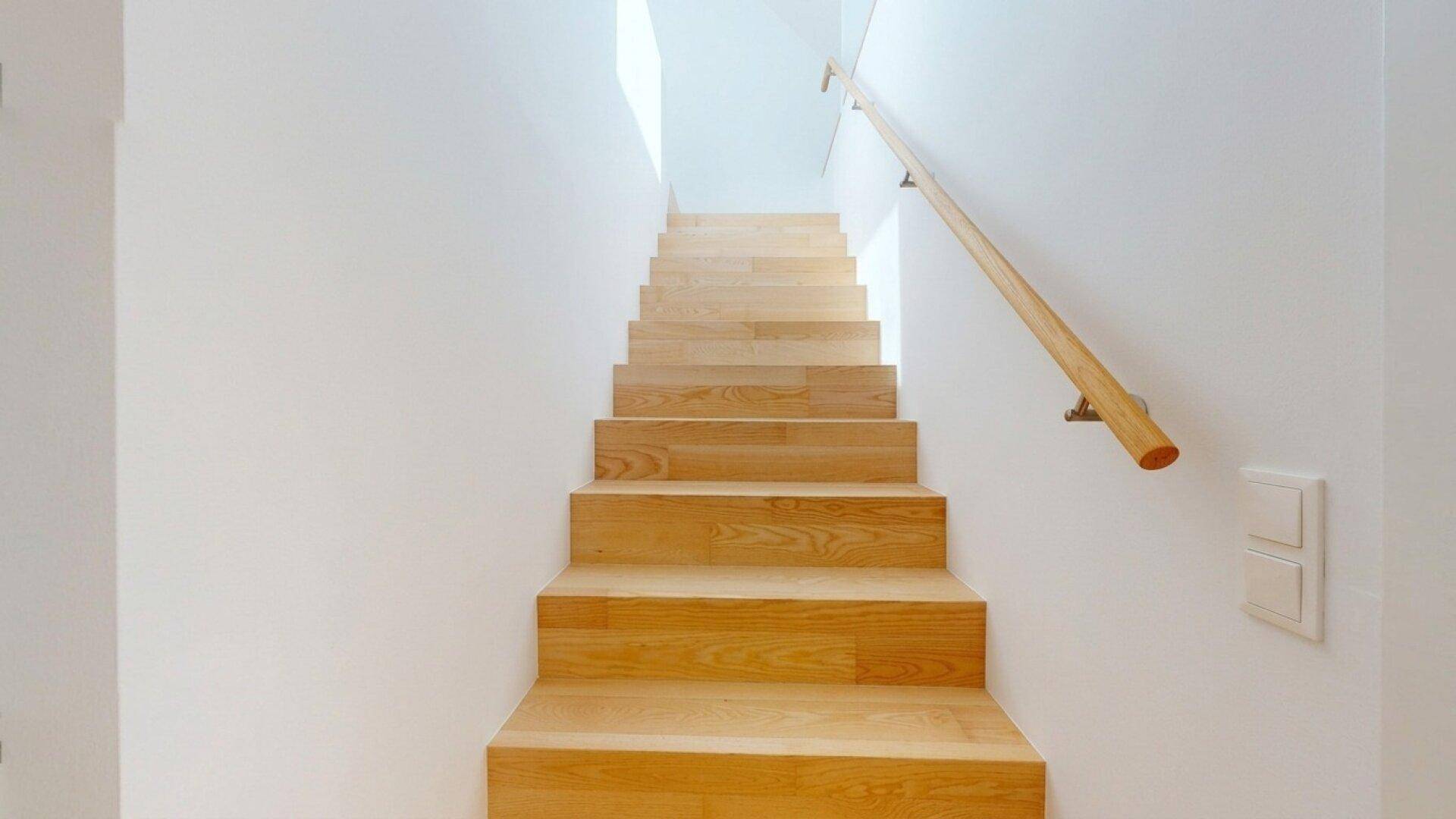 Helle Holztreppe mit schlichtem Geländer, die die verschiedenen Ebenen des Hauses verbindet.
