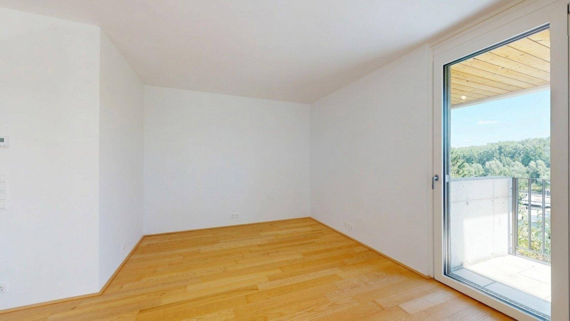 Helles Schlafzimmer mit Holzboden und direktem Zugang zum Balkon.