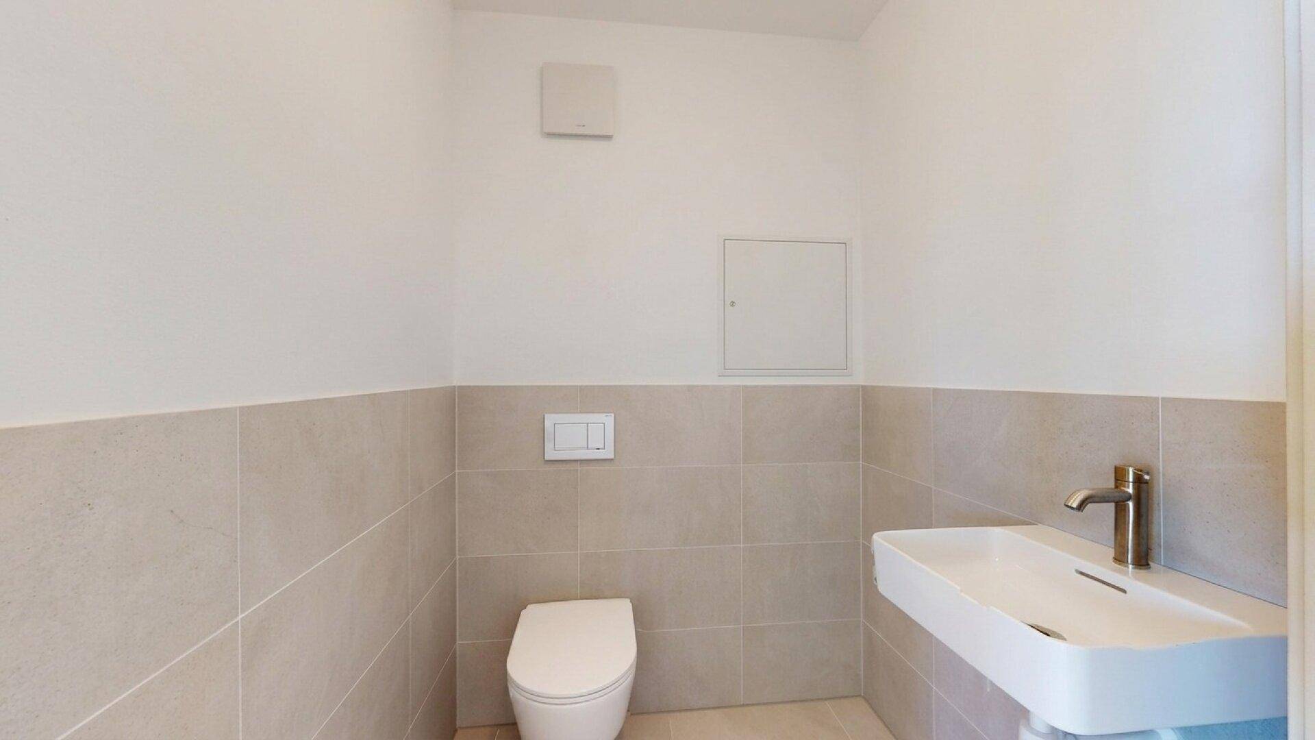 Modernes Gäste-WC mit Wand-WC, kleinem Waschbecken und hellen Fliesen.