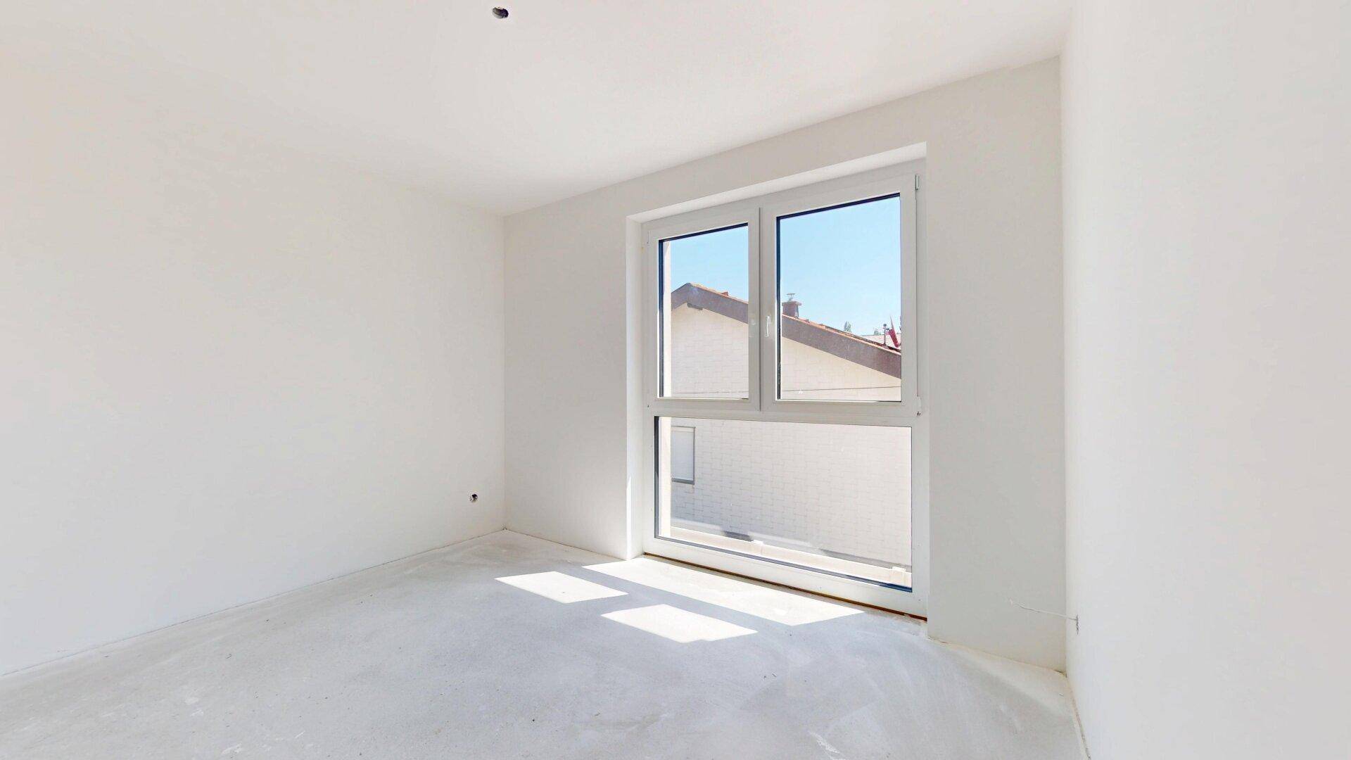 Helles, unfertiges Schlafzimmer mit großem Fenster und Blick auf die Umgebung, bereit zum Ausbau.