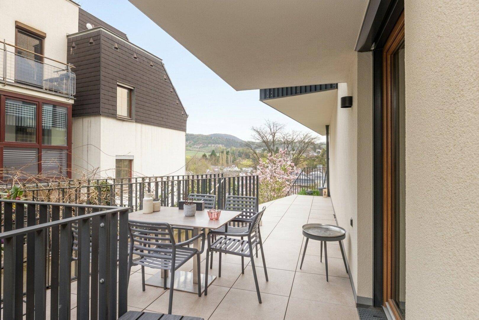 Heller Balkon mit Sitzgelegenheiten und weitem Blick auf die umliegende Landschaft und Hügel.