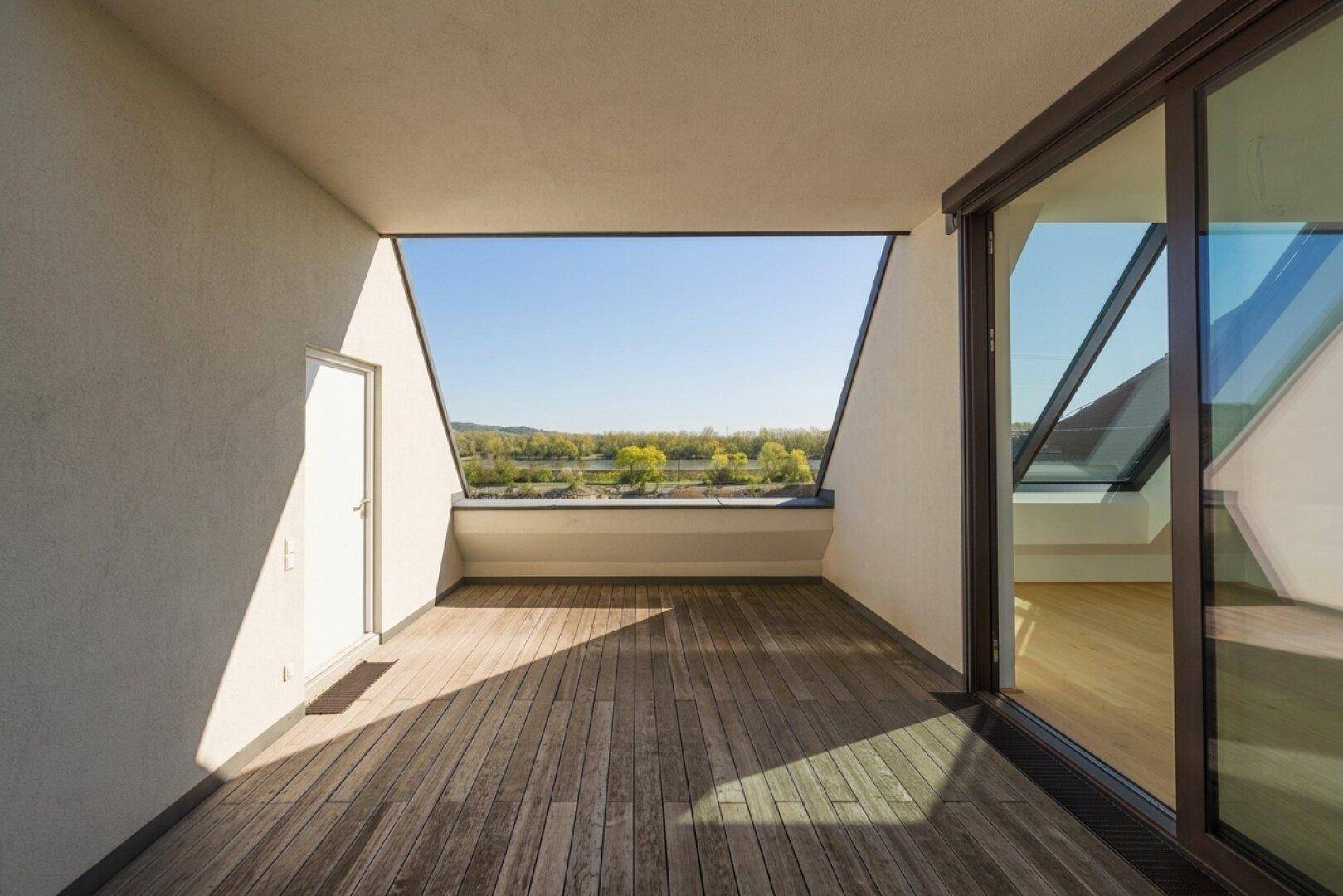 Geräumiger Balkon mit Holzdeck und weitem Blick auf das Wasser und die umliegende grüne Landschaft.