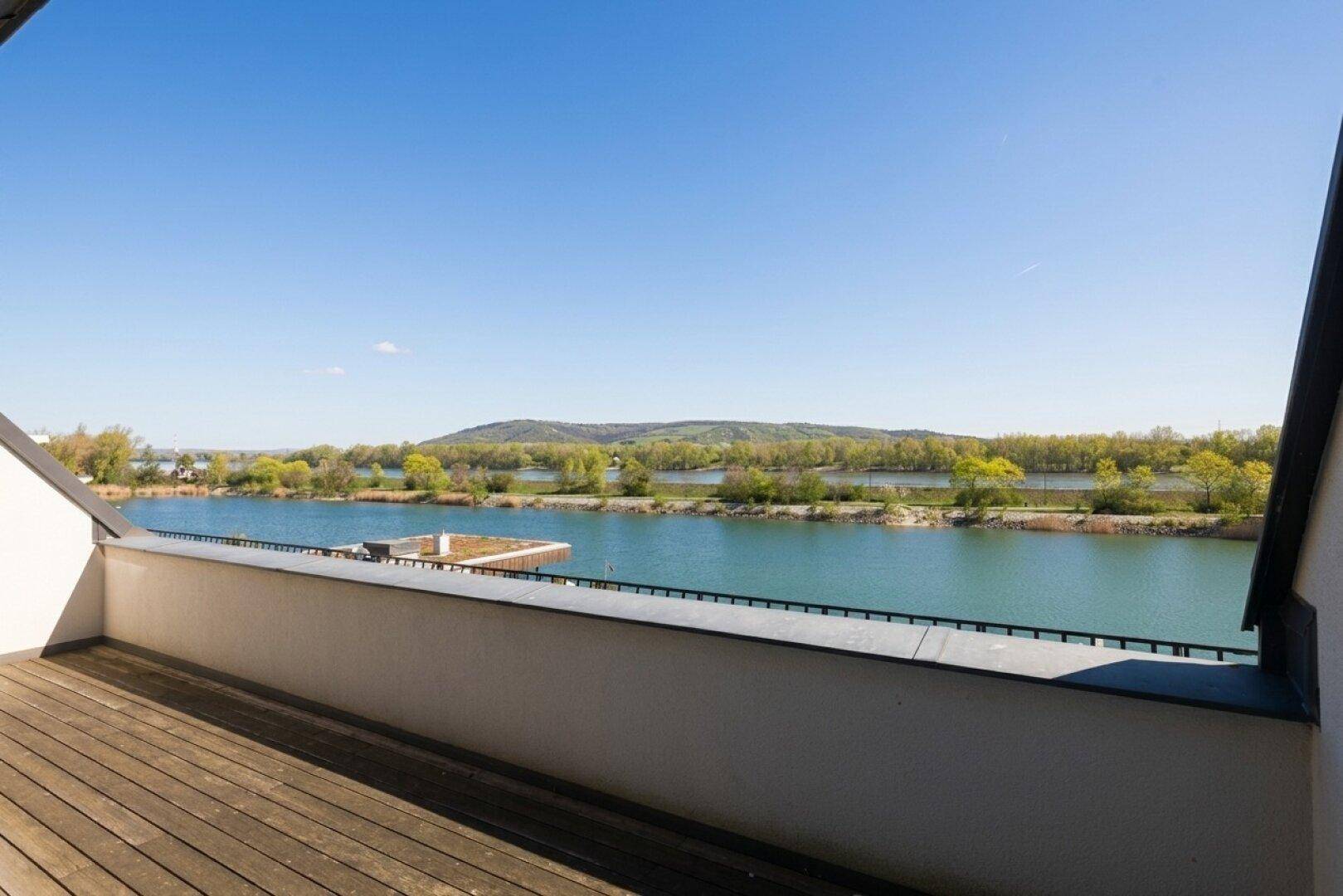 Atemberaubender Panoramablick vom Balkon auf den ruhigen See und die bewaldeten Hügel unter klarem Himmel.