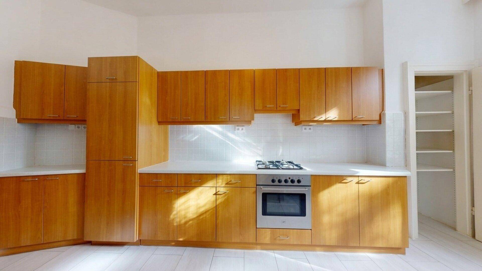 Funktionale Küche mit Holzschränken, Gasherd und weiß gefliestem Spritzschutz, bereit zur Nutzung.