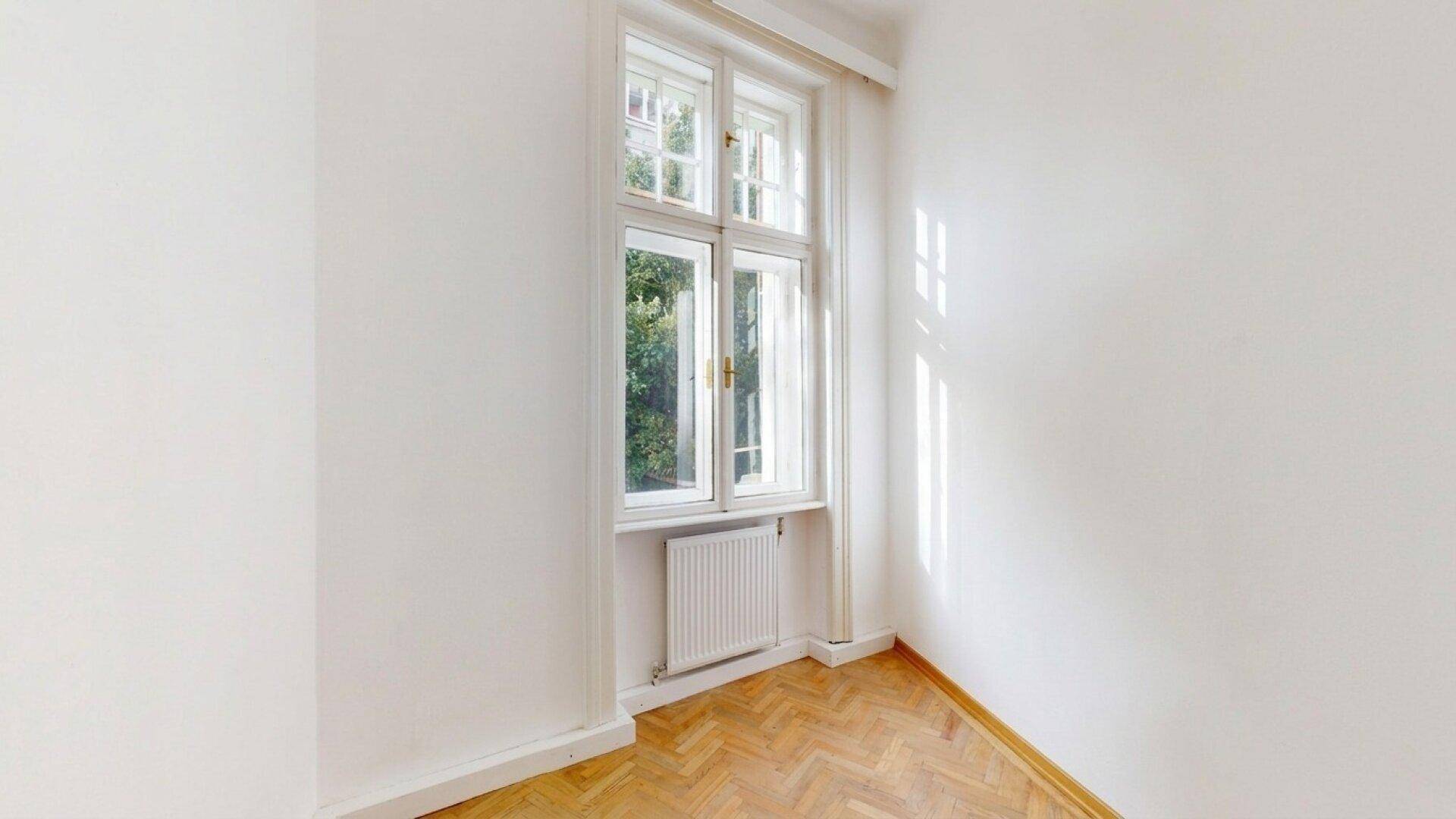 Kleines, helles Zimmer mit Fischgrätparkett und einem großen Fenster, ideal als Schlaf- oder Arbeitszimmer.