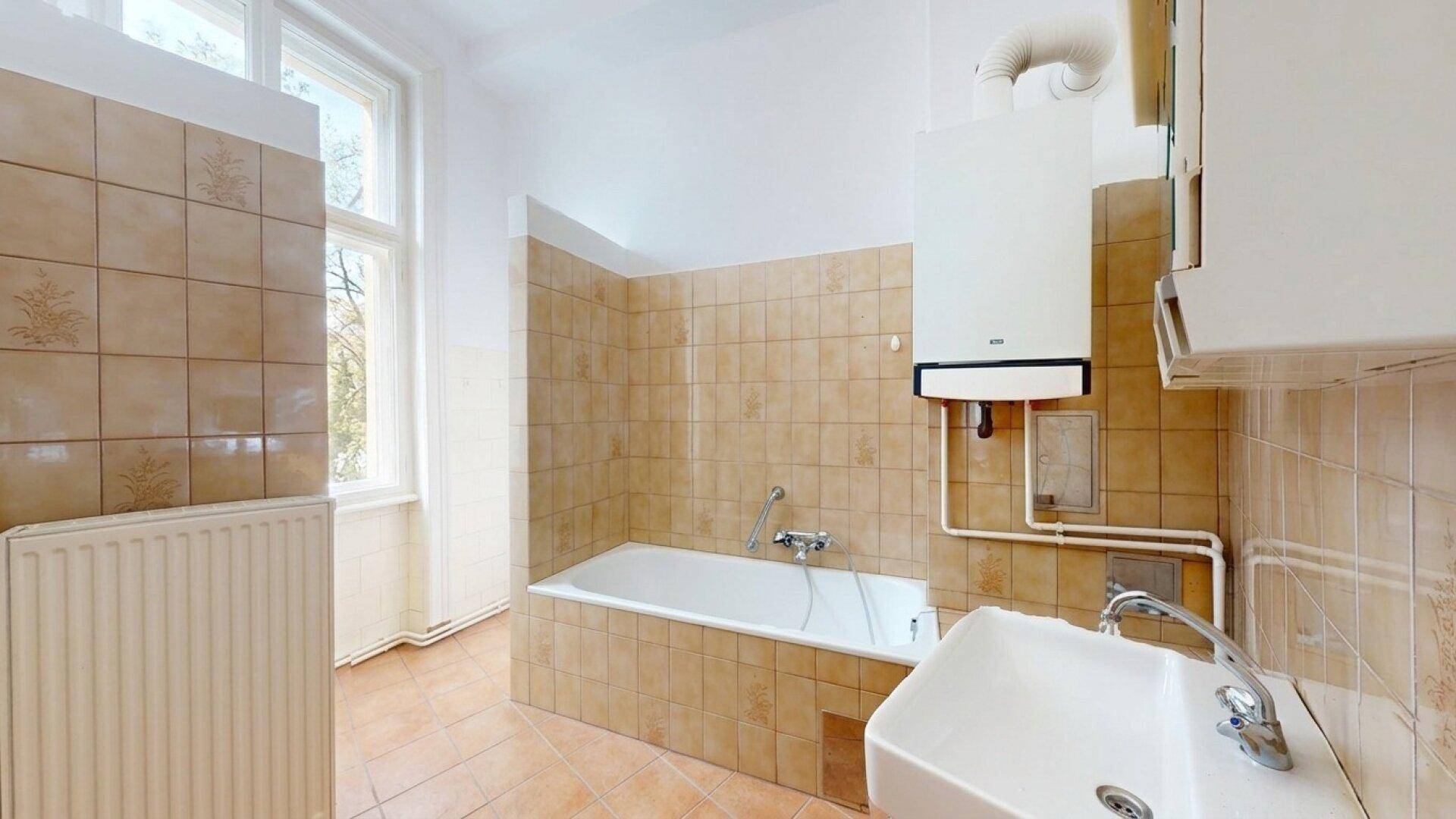 Badezimmer mit Badewanne, Waschbecken und beigefarbenen Fliesen, das ein Fenster für Belüftung bietet.