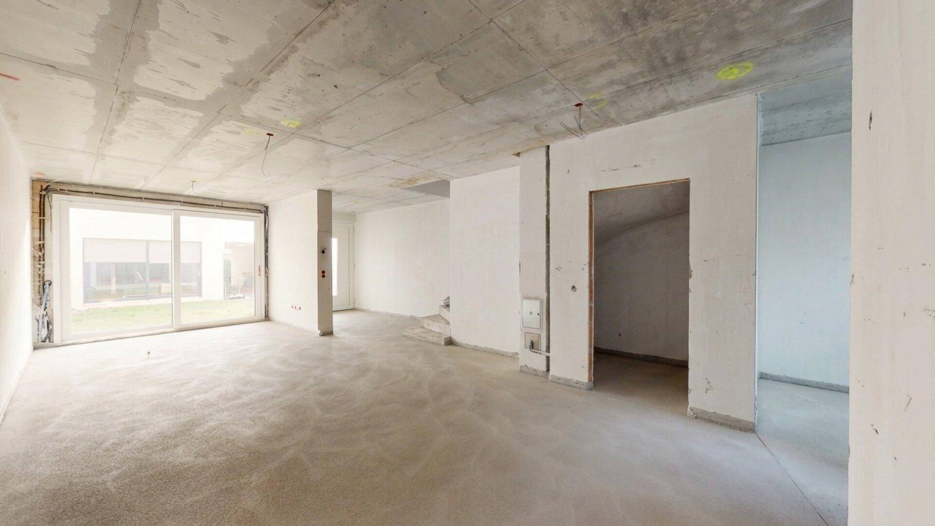 Geräumiger Rohbau-Raum im Erdgeschoss mit Blick in den Garten und viel Potenzial.