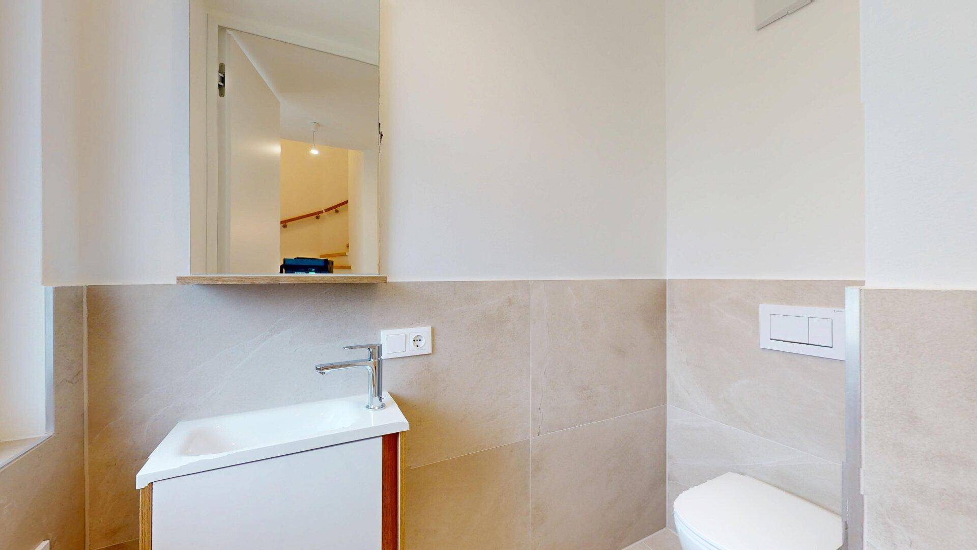Modernes Gäste-WC mit Einzelwaschbecken, Wand-WC und hellen Fliesen.