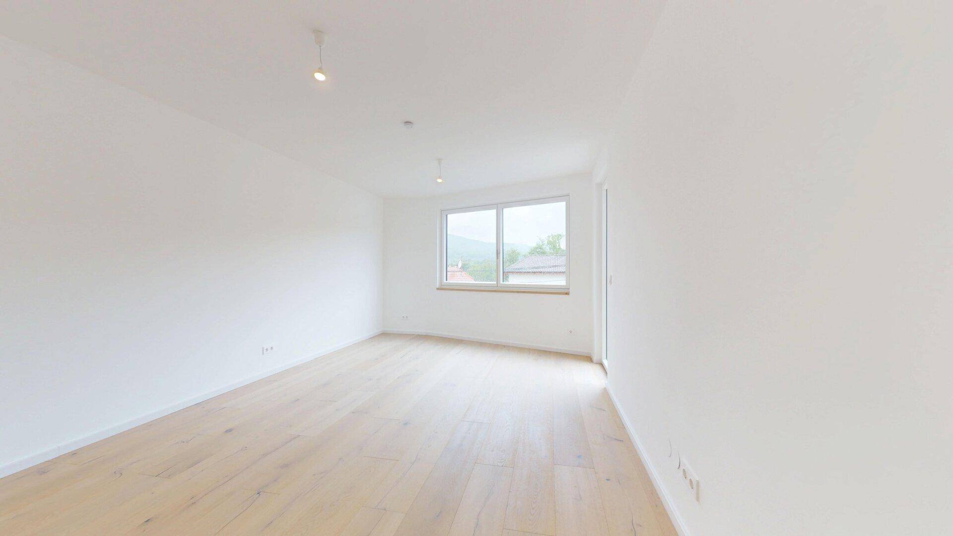 Geräumiges Zimmer mit Holzboden und Fenster, ideal als Schlaf- oder Arbeitszimmer nutzbar.