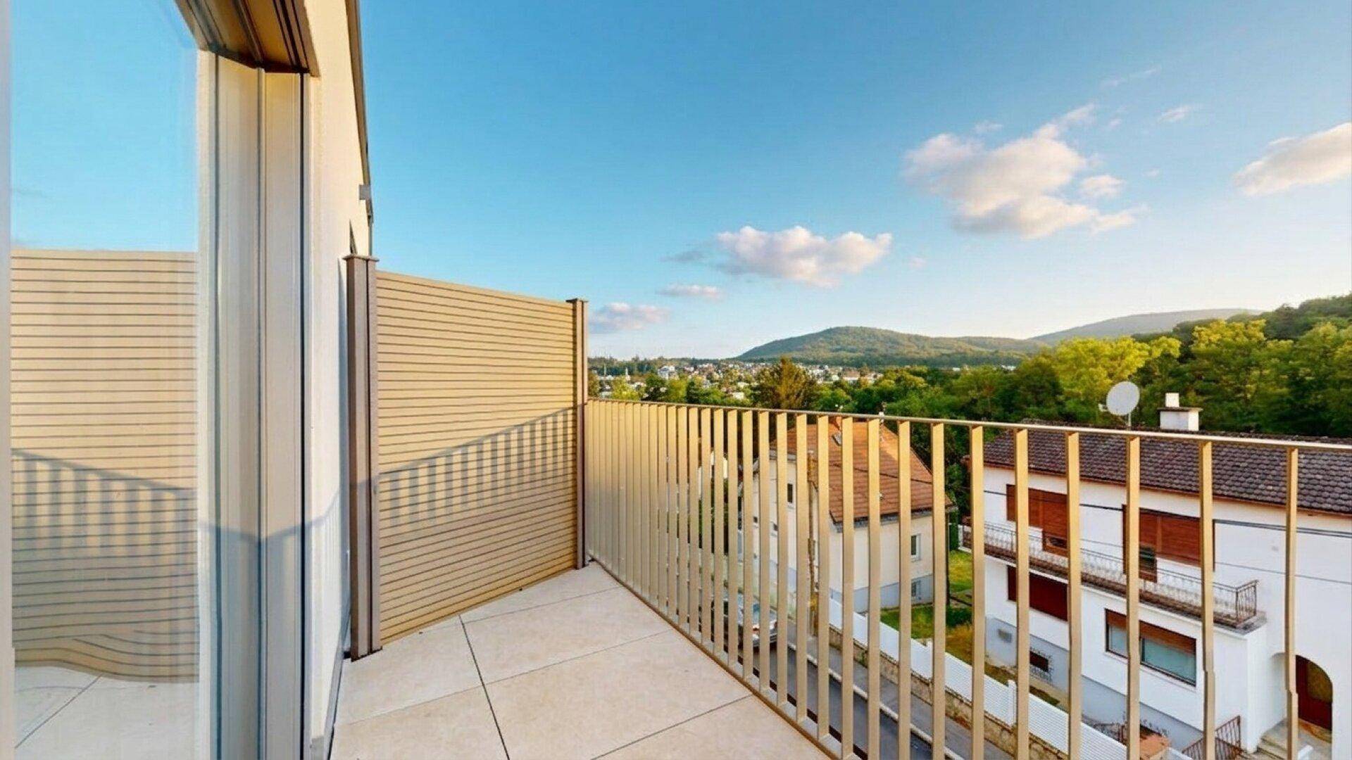 Heller Balkon mit modernem Geländer und weitem Blick über die Stadt und grüne Hügel.