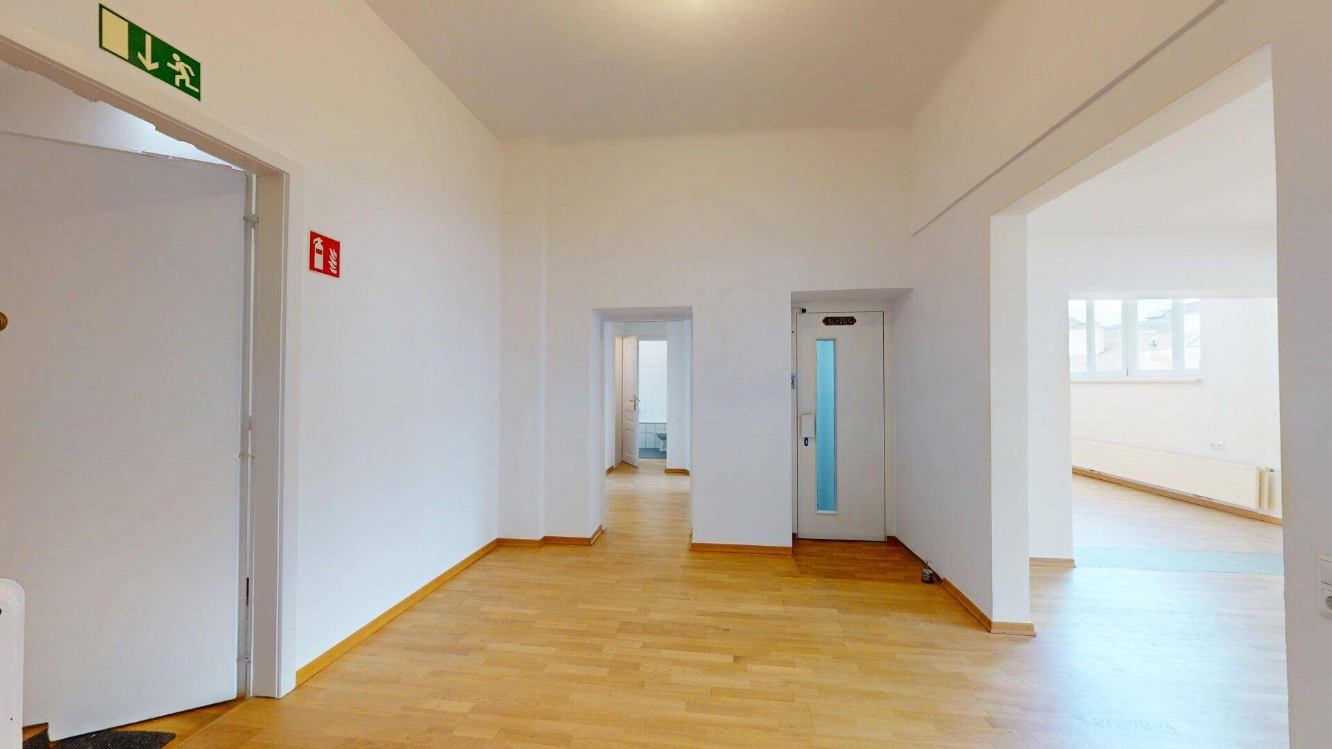 Heller Flur mit Holzfußboden und mehreren Türen, der zu verschiedenen Räumen führt.