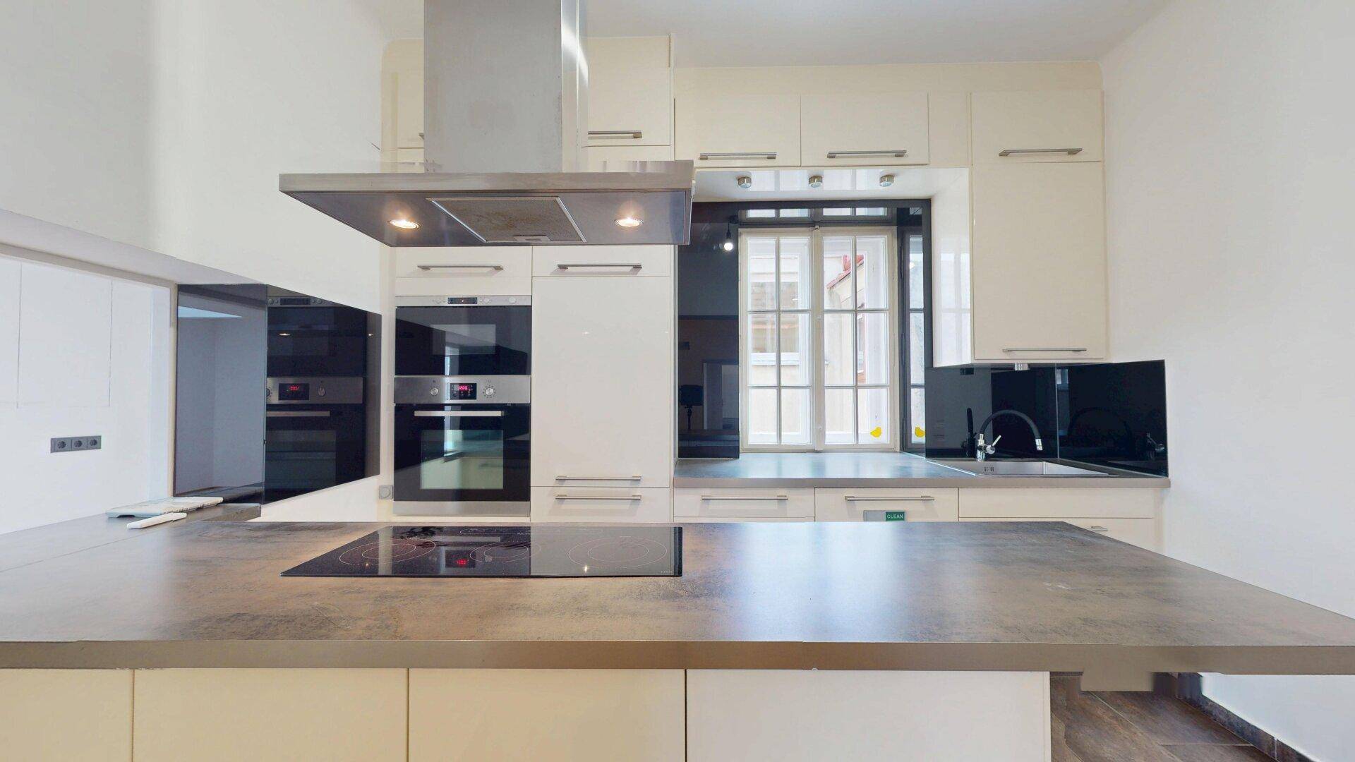 Moderne Einbauküche mit weißen Hochglanzfronten, dunkler Arbeitsplatte und Induktionskochfeld.
