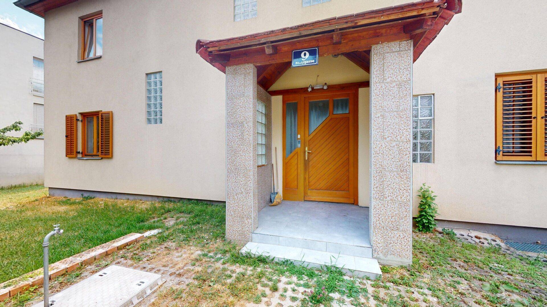 Eingangsbereich des Hauses mit überdachtem Portikus und Holztür.