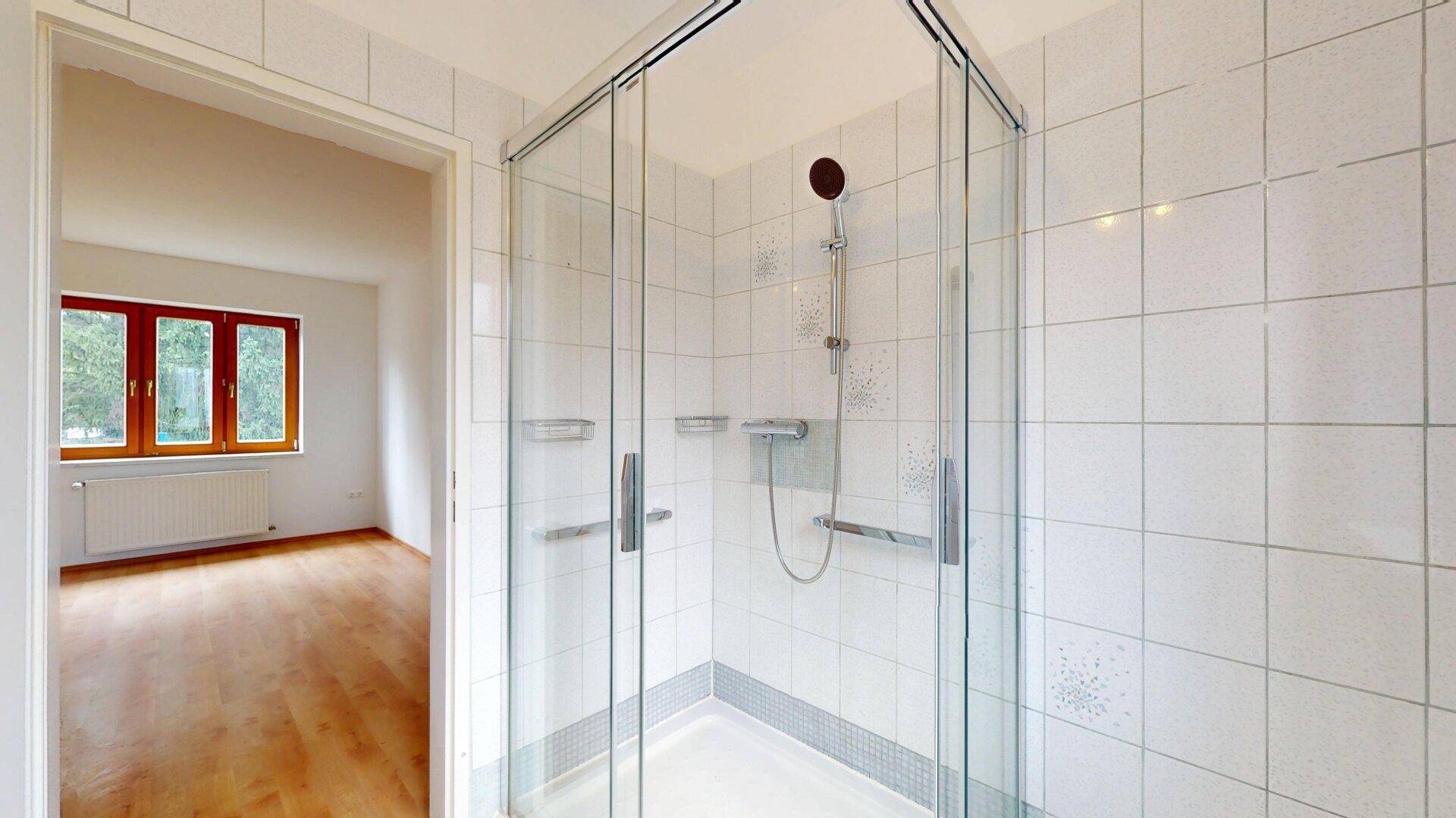 Modernisiertes Badezimmer mit Duschkabine und weißen Fliesen.