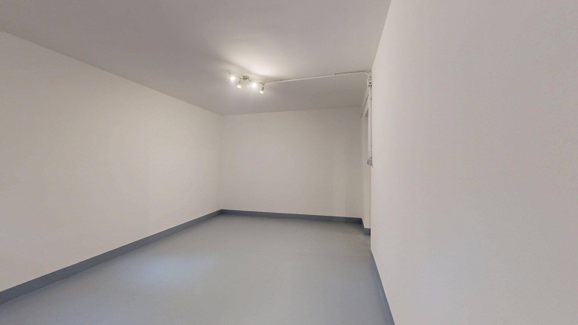 Einfacher Kellerraum mit grauem Boden und weiß gestrichenen Wänden.
