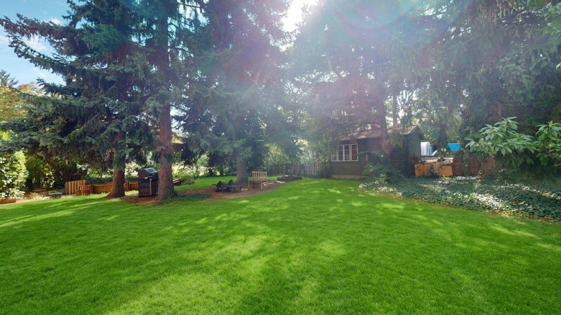 Großer, gepflegter Garten mit Rasenfläche und altem Baumbestand.