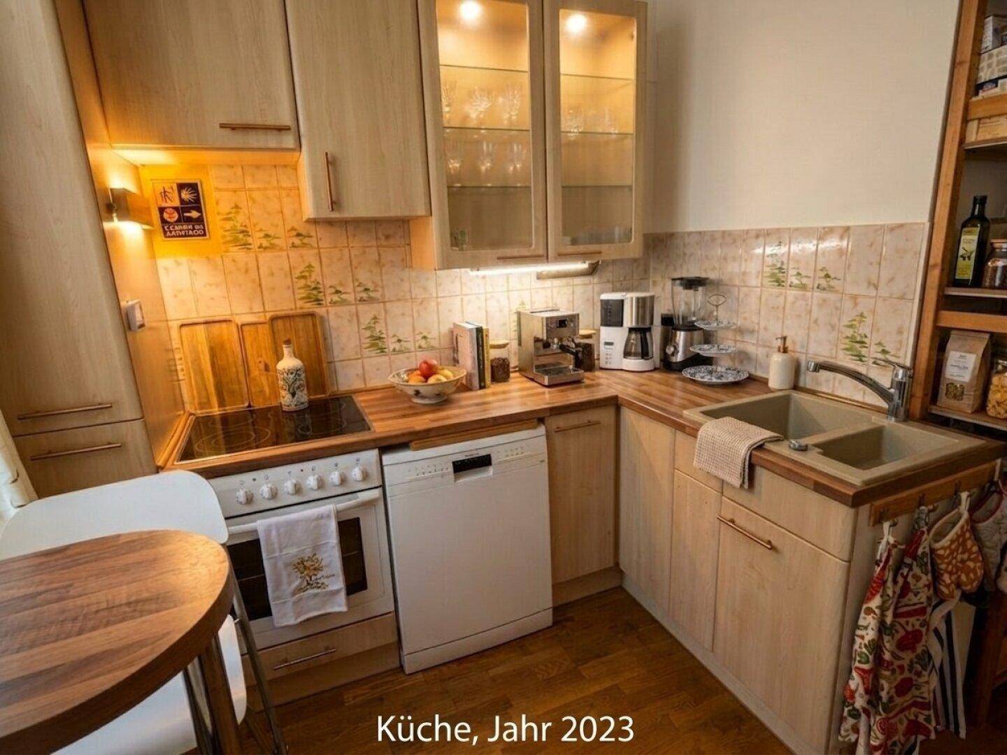 Helle Küche mit Holzschränken, kleinem Esstisch und modernen Einbaugeräten.