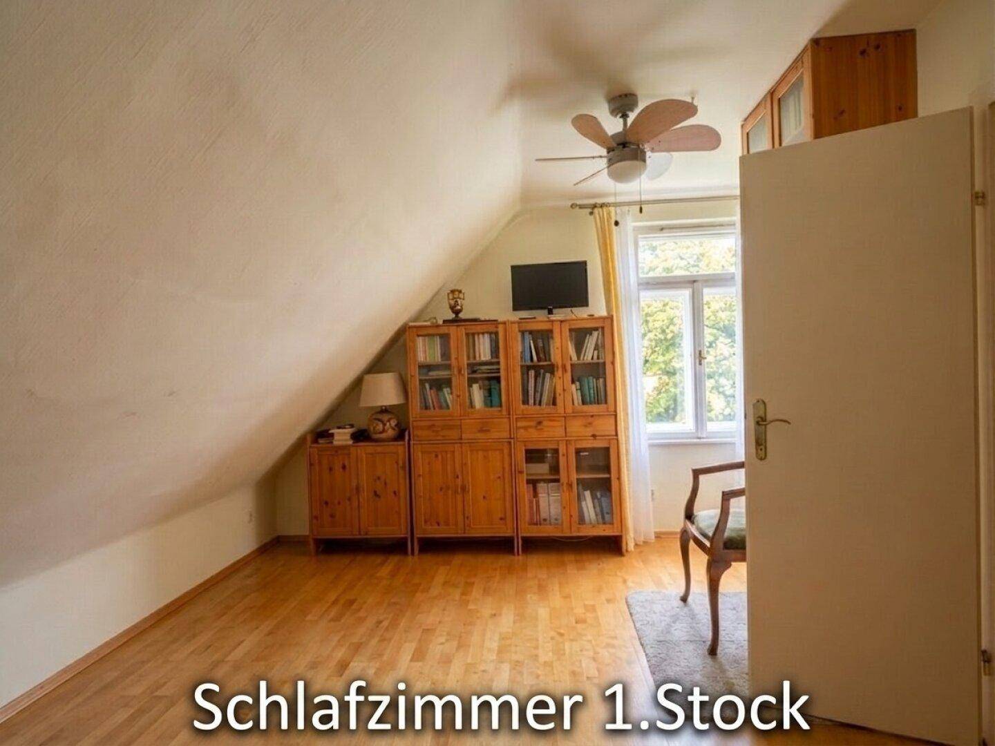 Schlafzimmer im Dachgeschoss mit schräger Decke, Holzfußboden und einem Deckenventilator.