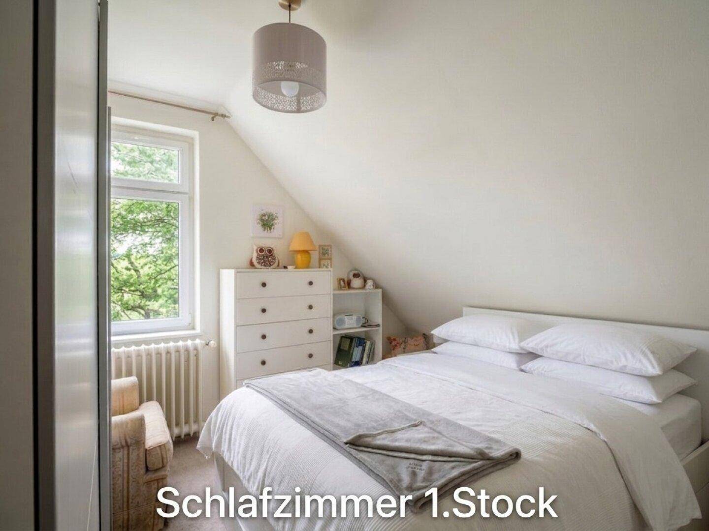 Helles Schlafzimmer im Dachgeschoss mit schräger Decke, weißen Wänden, Bett und Fenster.