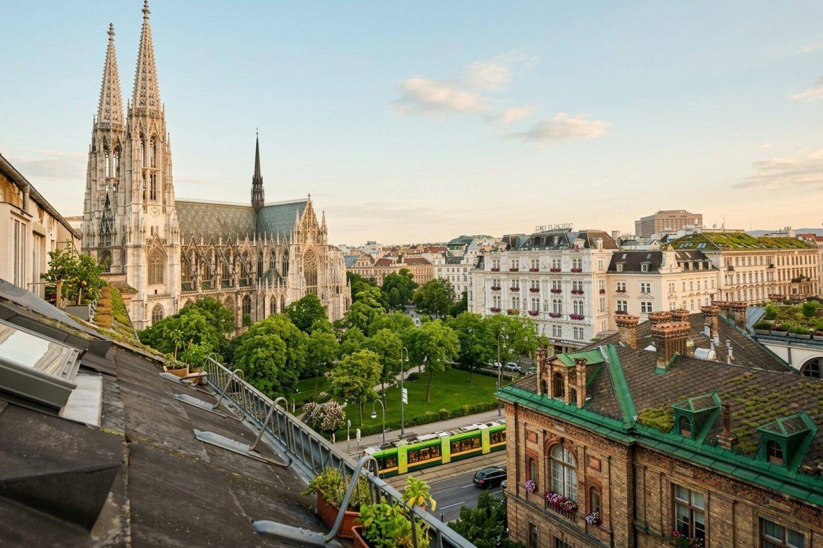 Beeindruckender Panoramablick über die Wiener Dächer, mit der majestätischen Votivkirche, grünen Parks und einer belebten Straße.