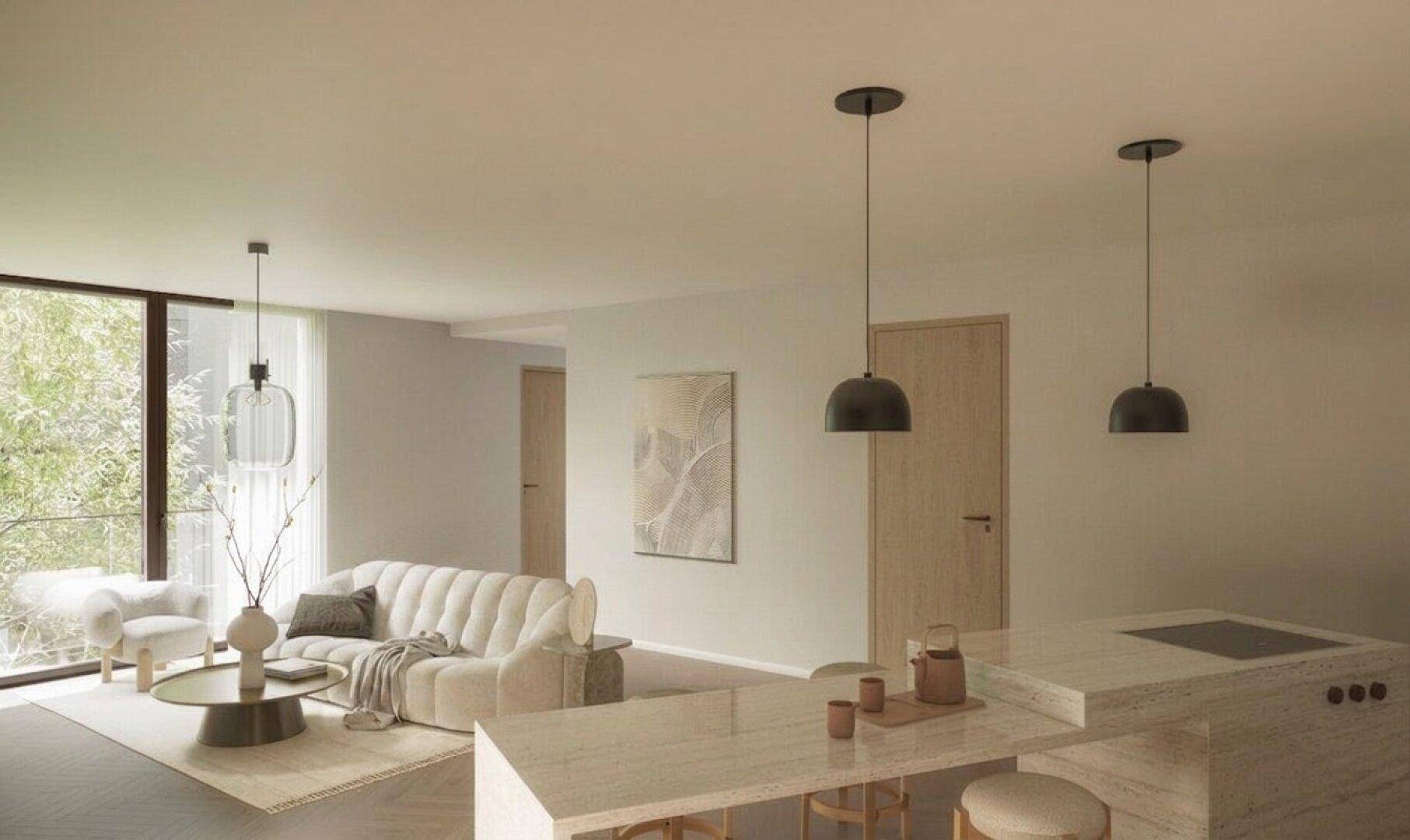 Heller offener Wohnbereich mit beigem Sofa, Kücheninsel und großen Fenstern.