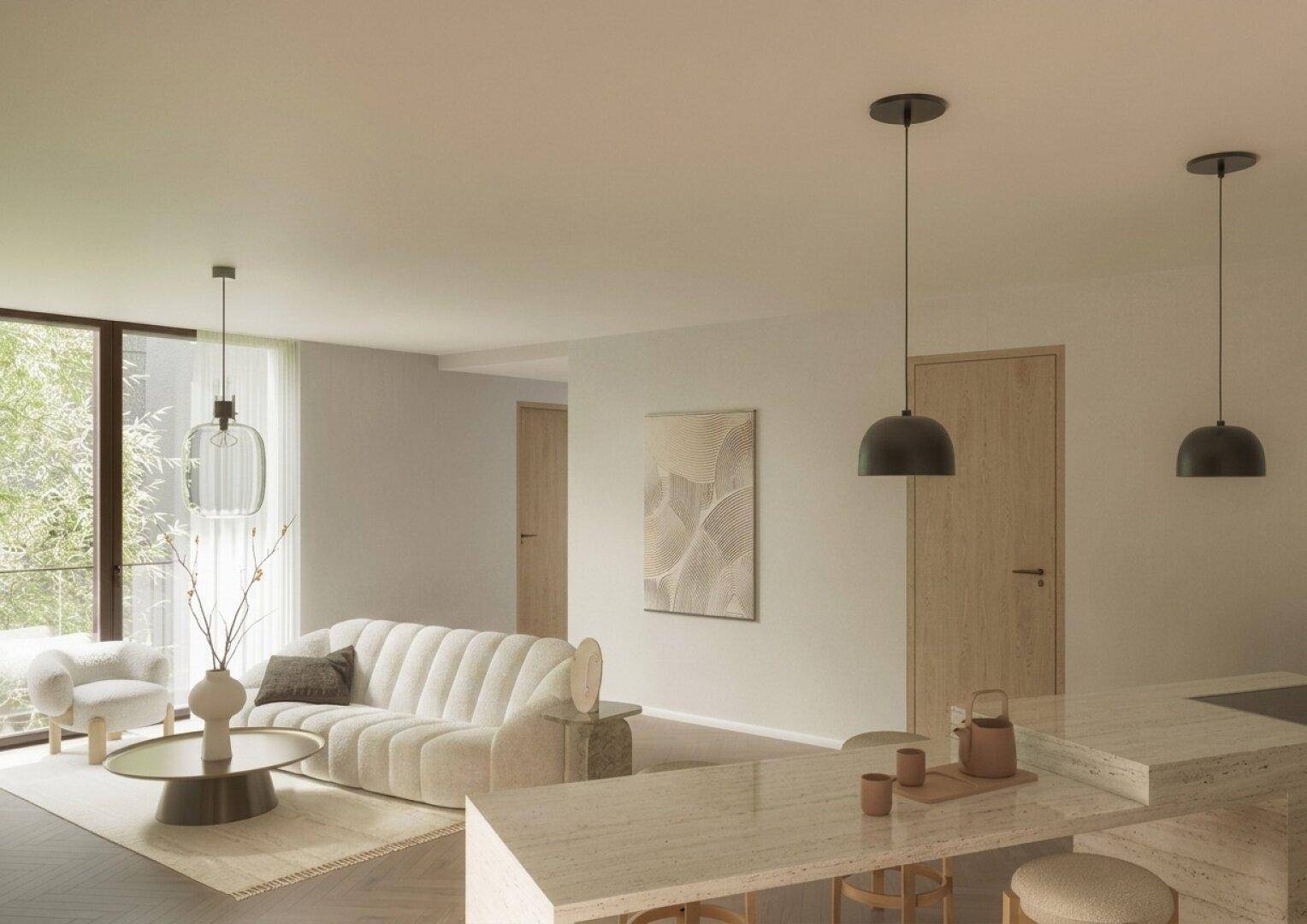 Heller offener Wohnbereich mit beigem Sofa, Kücheninsel und großen Fenstern.