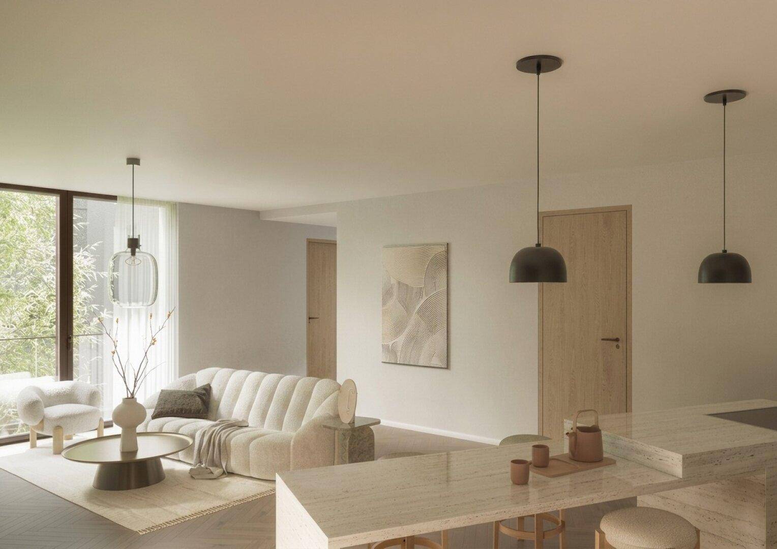 Heller Wohnbereich mit beigem Sofa, moderner Kücheninsel und großen Fenstern.