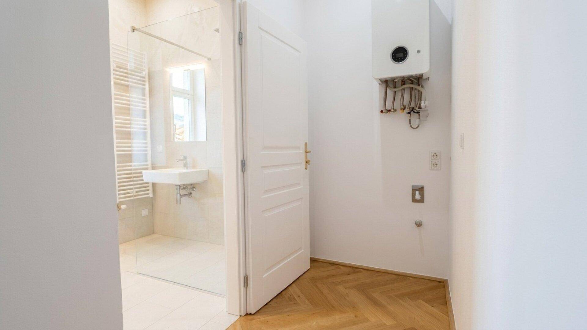 Bereich mit Heiztherme und Anschlussmöglichkeiten, angrenzend an ein modernes Badezimmer mit Dusche.