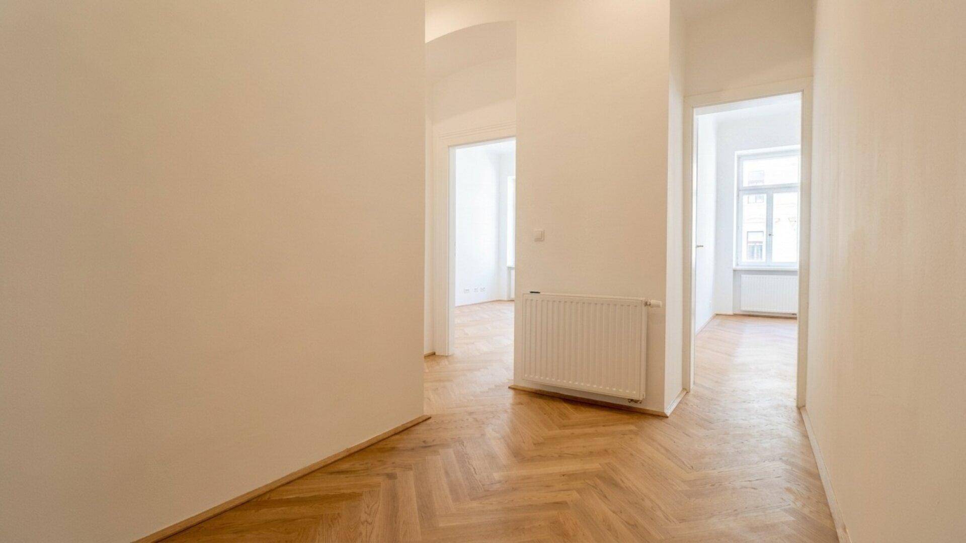 Geräumiger Flur mit Fischgrätparkett und Zugang zu verschiedenen Räumen der Wohnung.