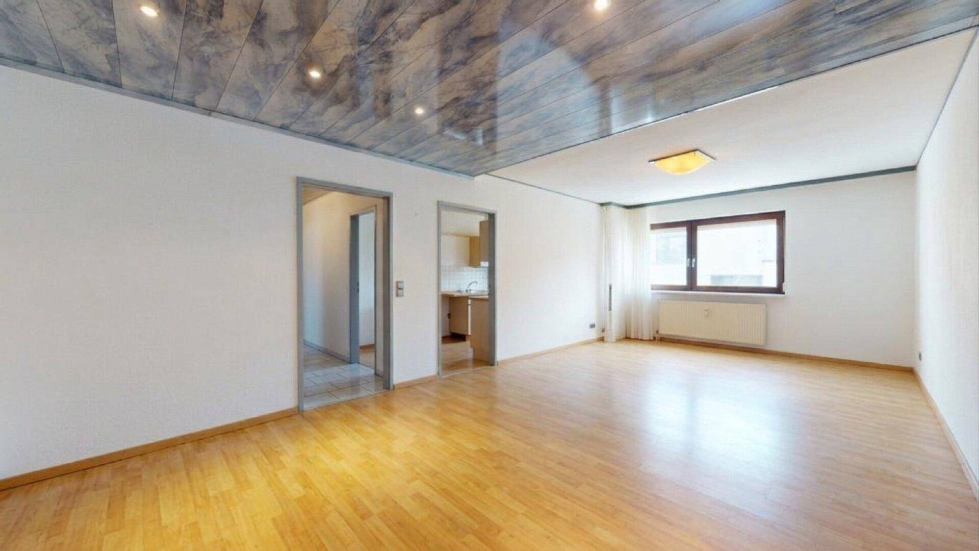 Geräumiges Zimmer mit Holzparkettboden und Zugang zu angrenzenden Räumen.
