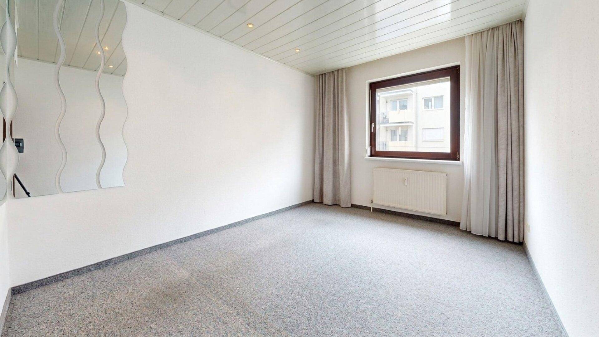 Helles Schlafzimmer mit Teppichboden und dekorativen wellenförmigen Spiegeln an der Wand.