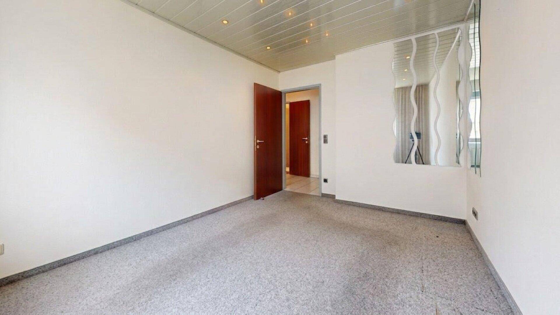 Schlafzimmer mit Teppichboden und einer offenen Holztür, die den Zugang ermöglicht.