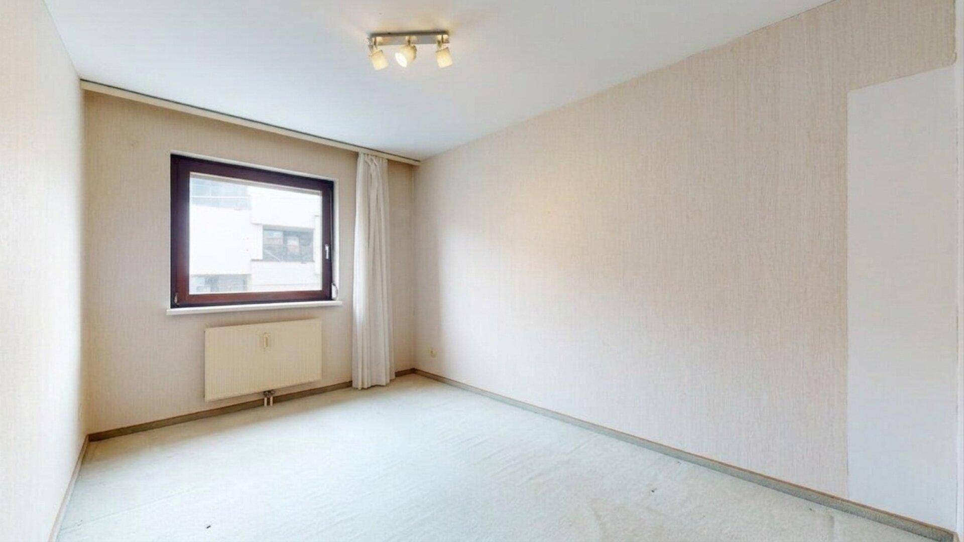 Schlafzimmer mit hellem Teppichboden und einem Fenster für natürliches Licht.