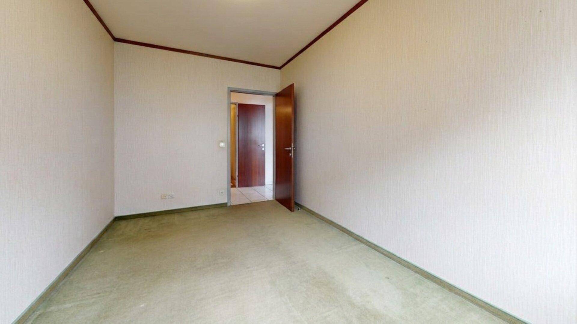 Schlafzimmer mit grünem Teppichboden und einer offenen Holztür.