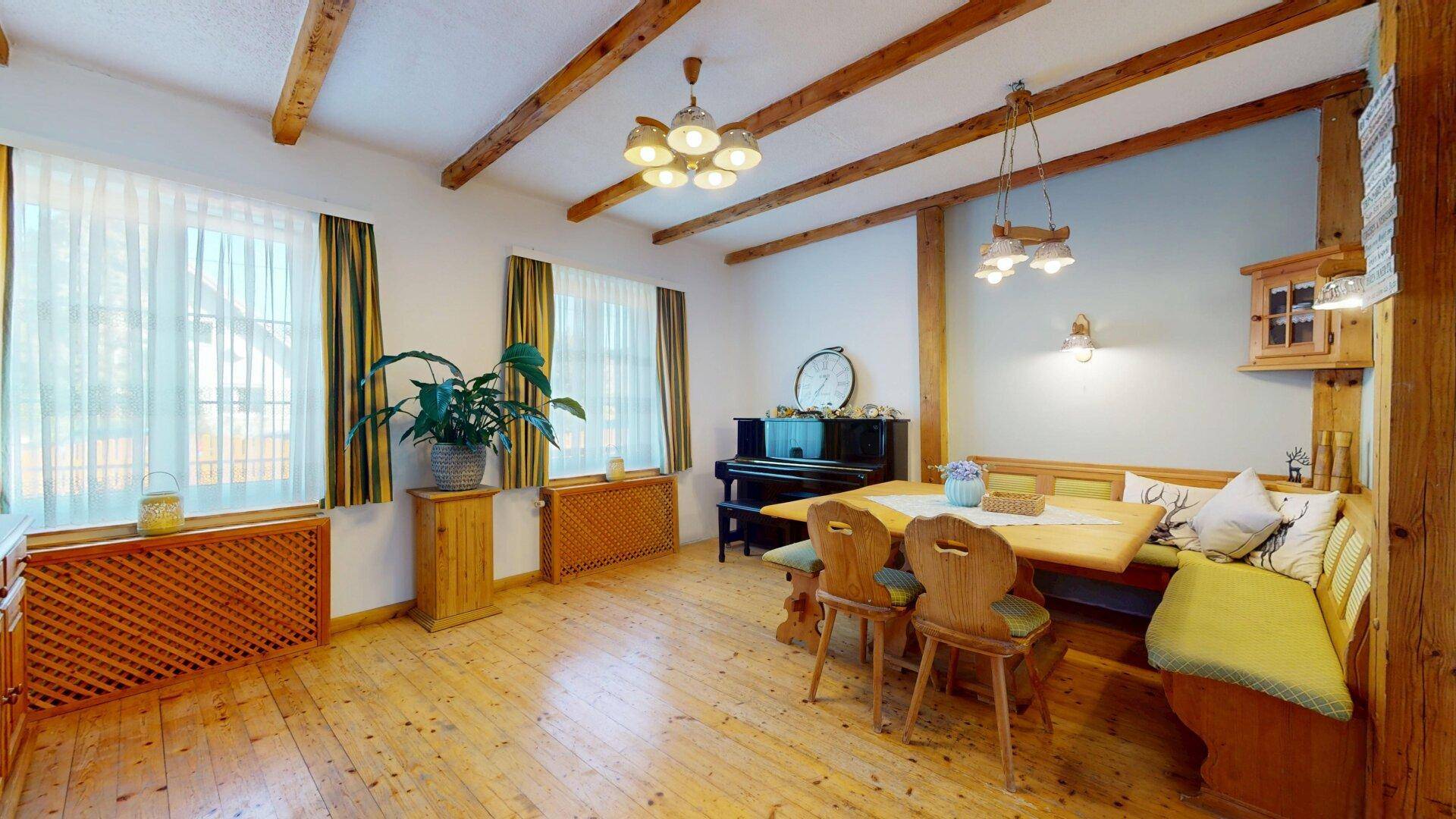 Traditioneller Essbereich mit Holzbalken, rustikalen Möbeln und einem Klavier.