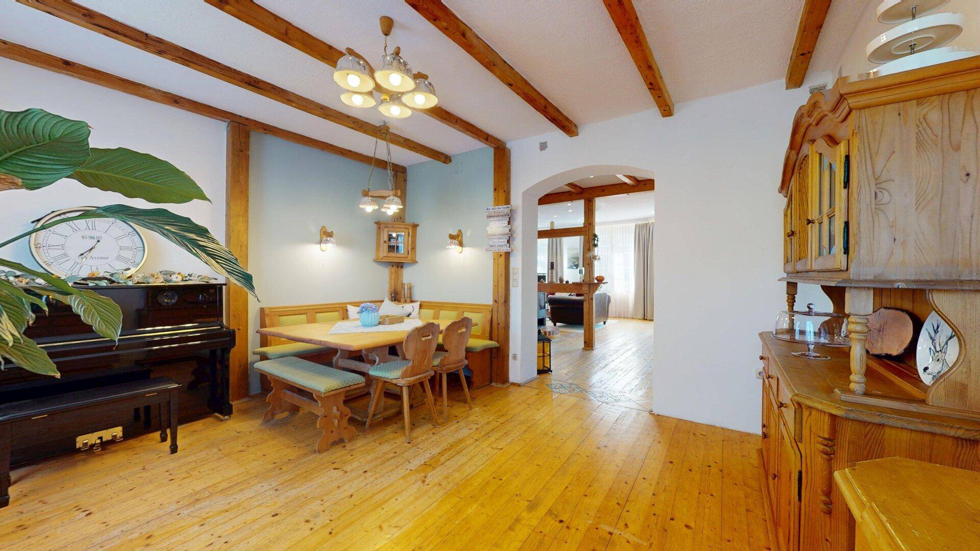 Rustikaler Essbereich mit Holzbalken, traditionellen Möbeln und einem Durchgang zum Wohnzimmer.