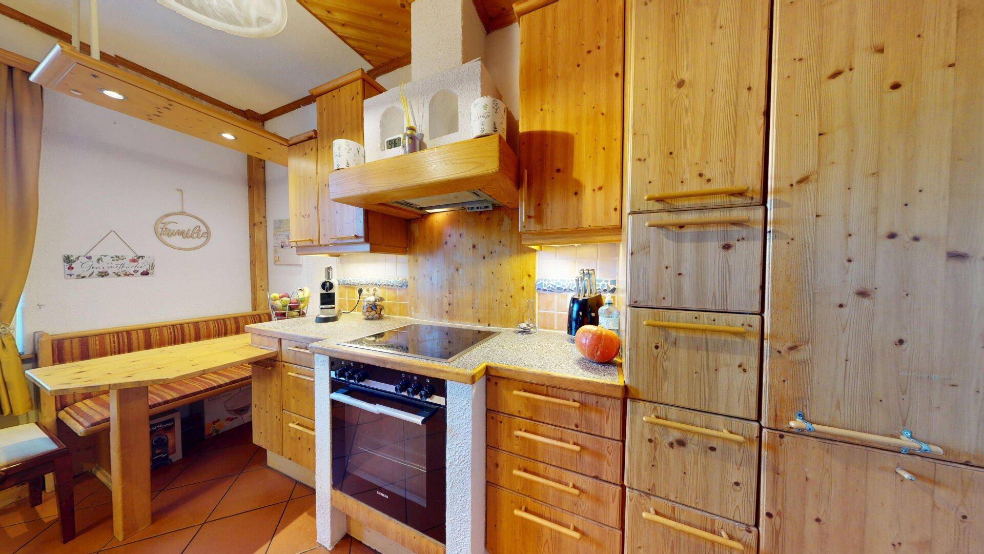 Gemütliche Küche mit Holzschränken, Einbaugeräten und einer kleinen Essecke.