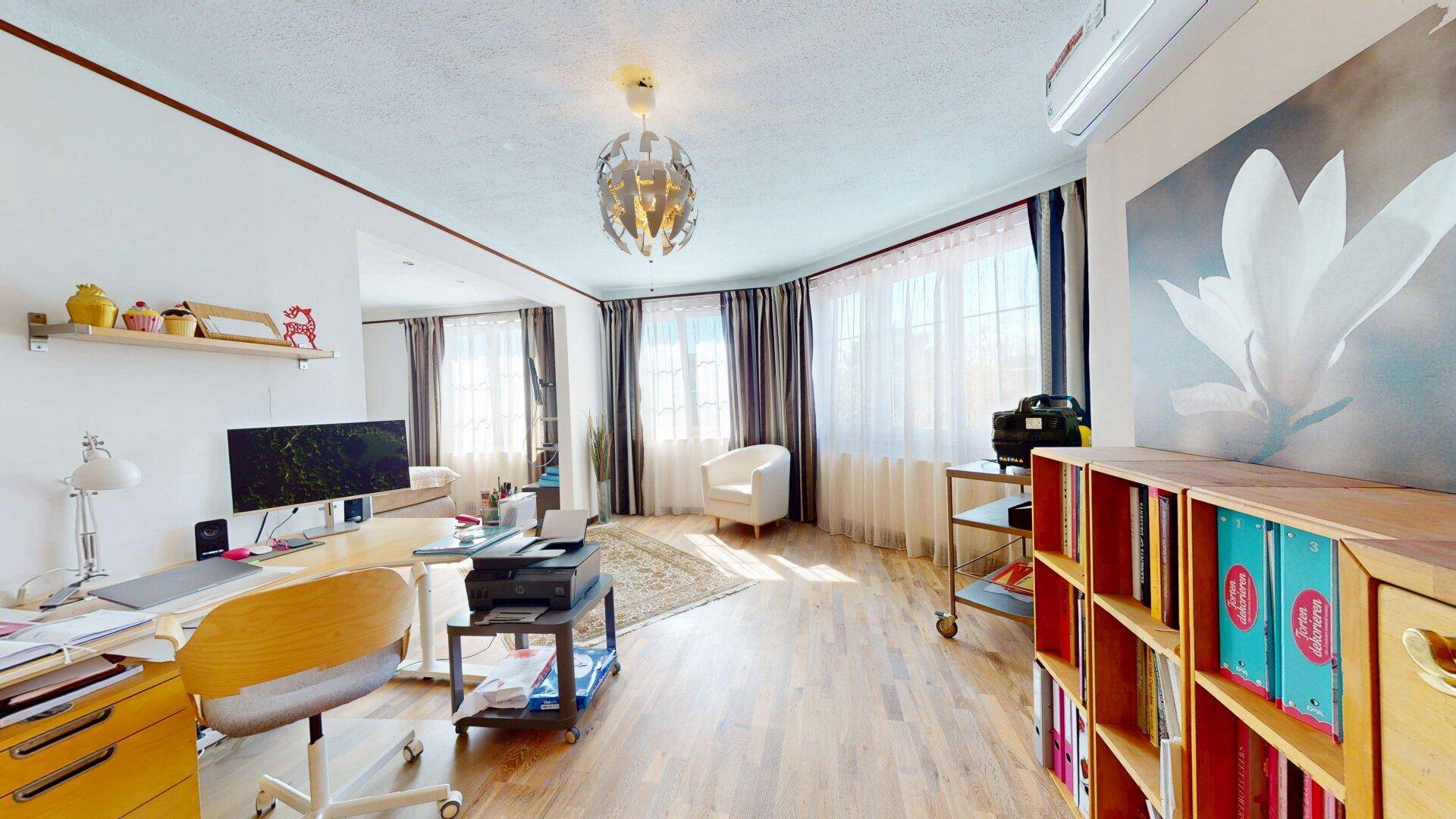 Helles Arbeitszimmer mit Schreibtisch, Computer und großen Fenstern für viel Tageslicht.