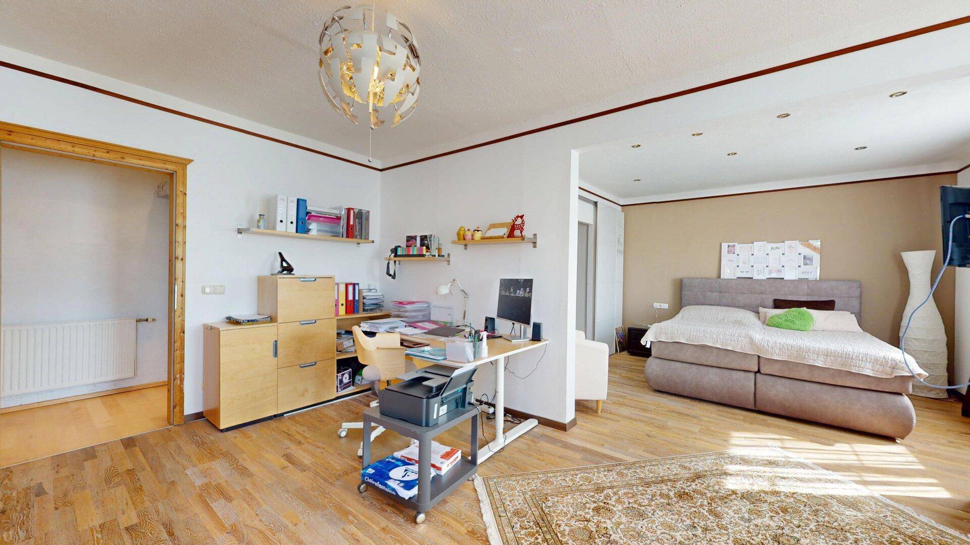 Kombinierter Schlaf- und Arbeitsbereich mit Doppelbett und Schreibtisch.