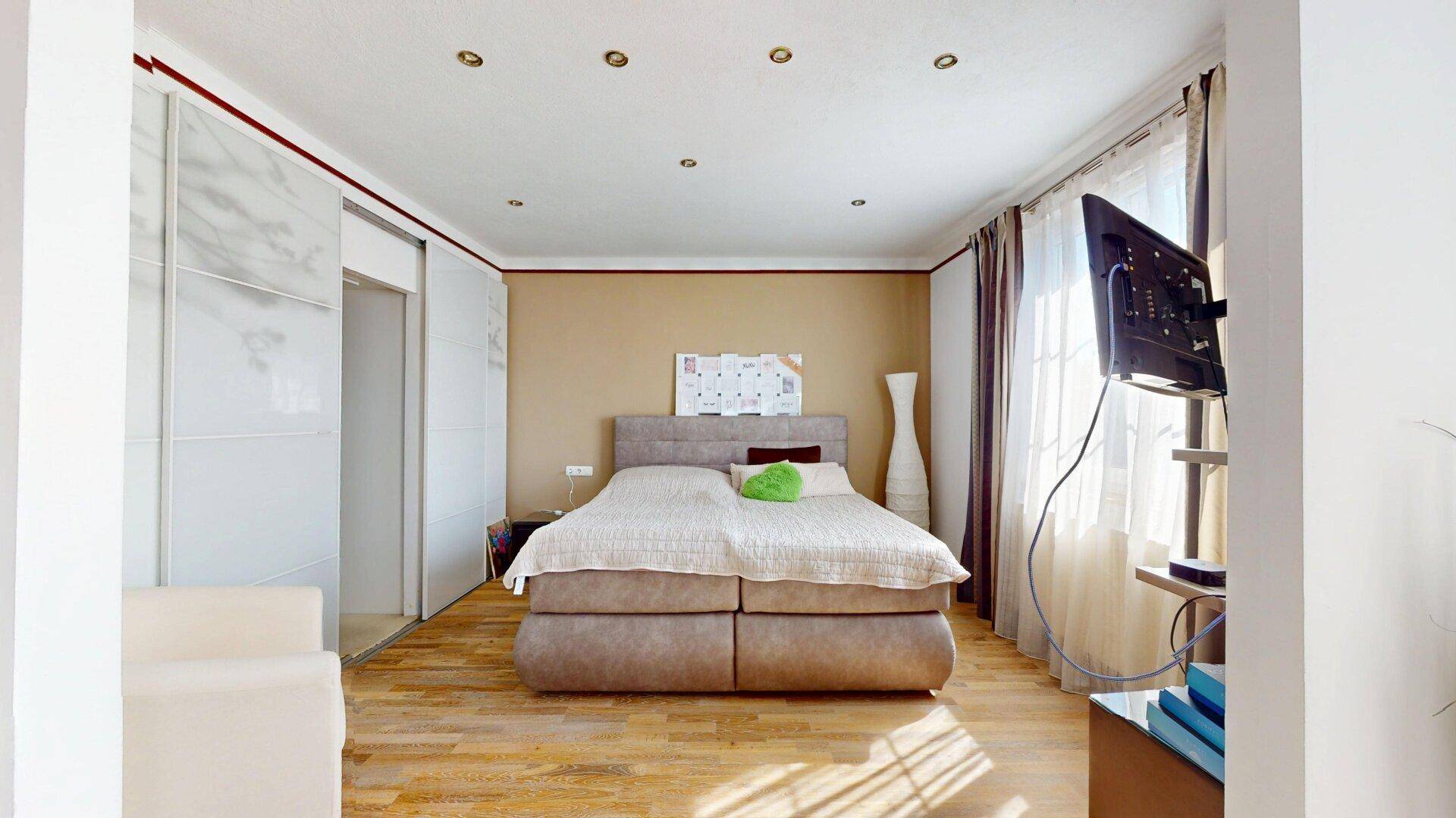 Geräumiges Schlafzimmer mit großem Bett, Holzboden und integrierter Deckenbeleuchtung.