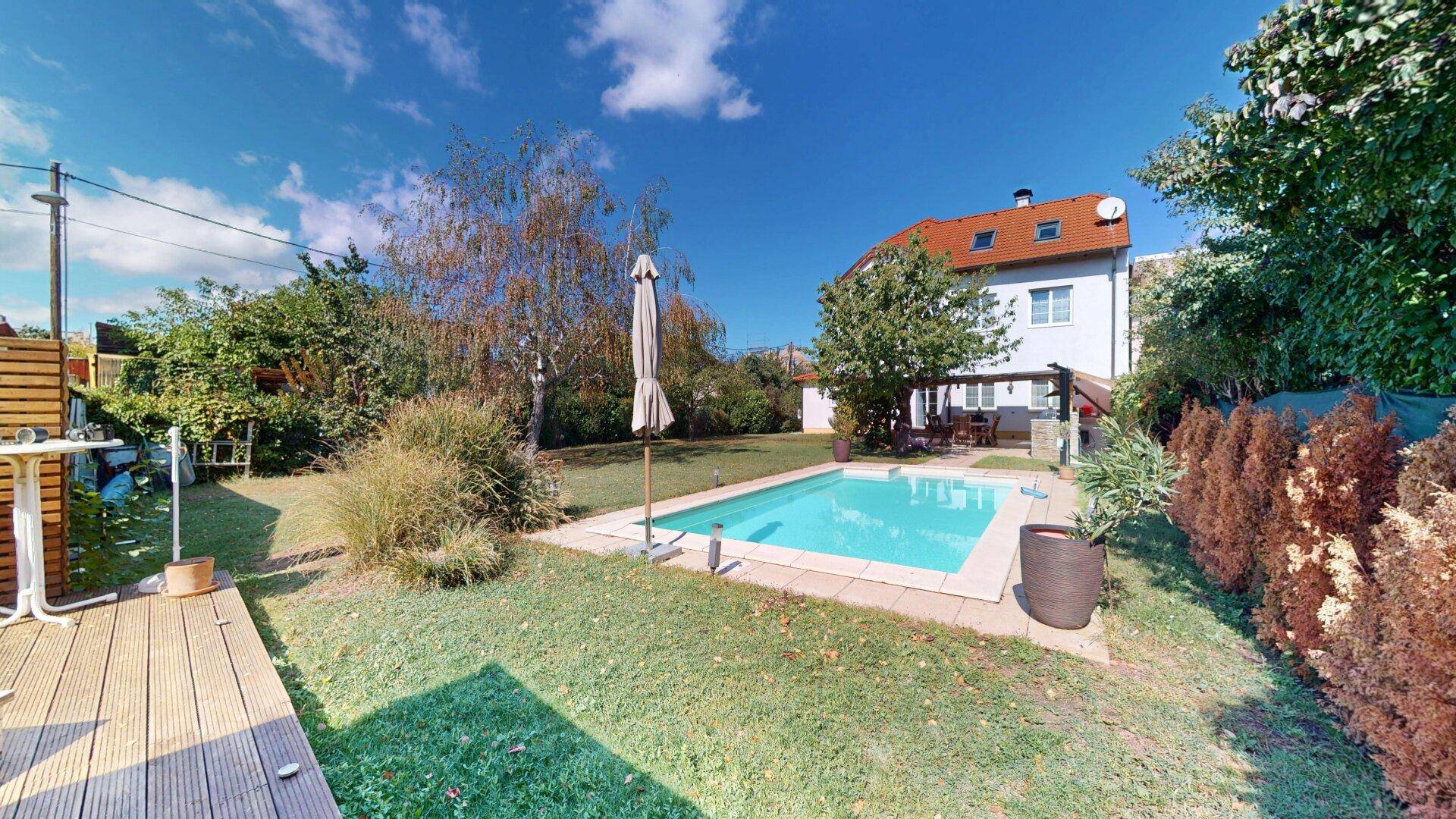 Großer Garten mit Swimmingpool, Rasenfläche und altem Baumbestand für Entspannung.