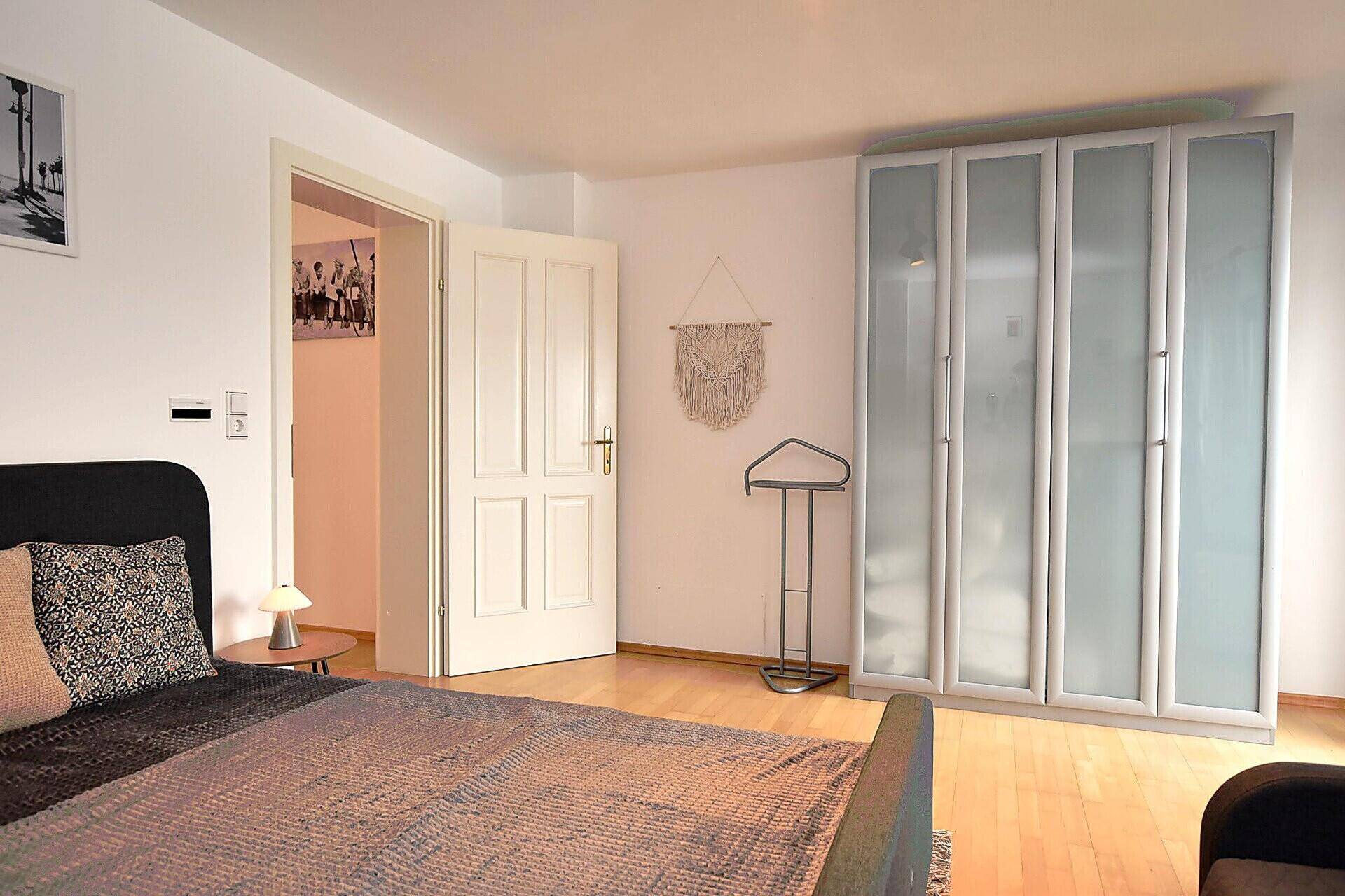 Schlafzimmer mit Doppelbett, Einbauschrank und hellem Holzfußboden.