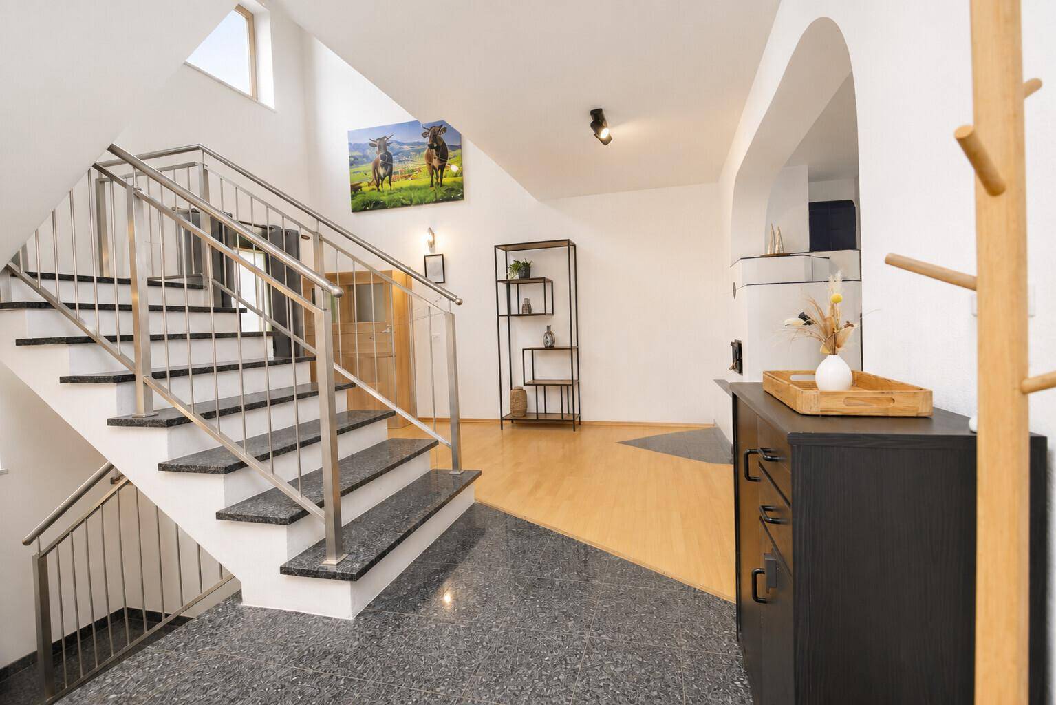Geräumiger Eingangsbereich mit moderner Treppe, Holzboden und dekorativen Elementen.