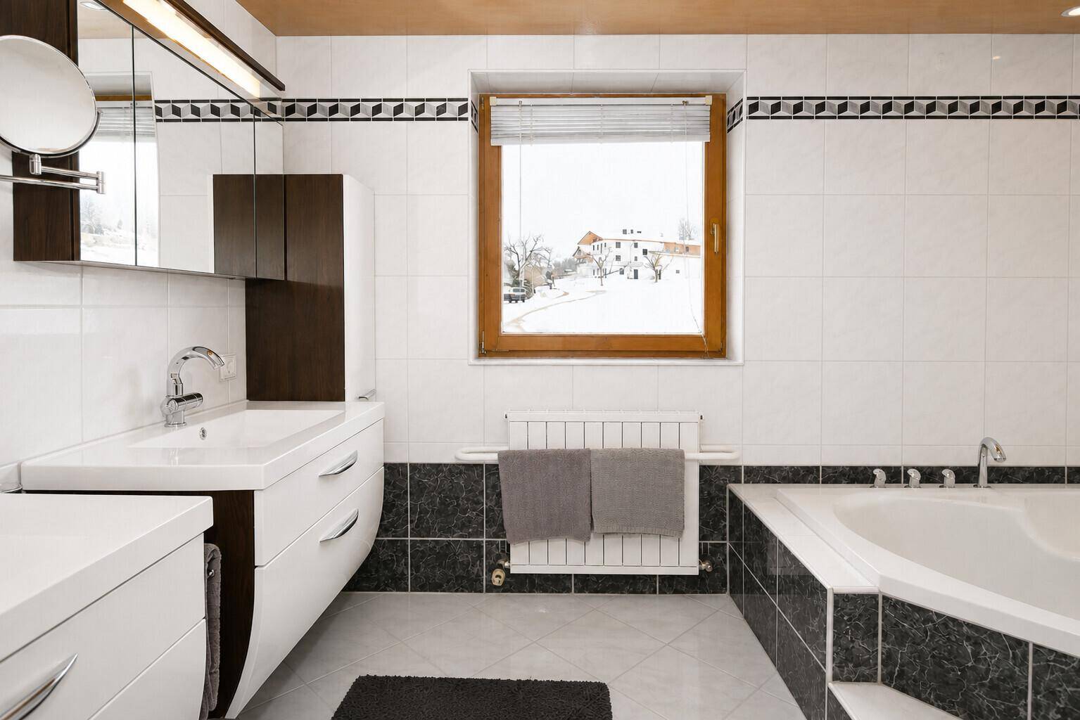 Geräumiges Badezimmer mit Badewanne, Doppelwaschbecken und Fenster.