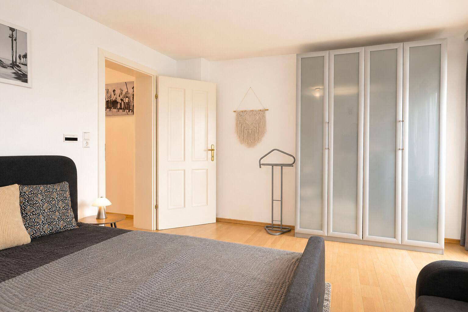 Helles Schlafzimmer mit Doppelbett, Kleiderschrank und Holzboden.